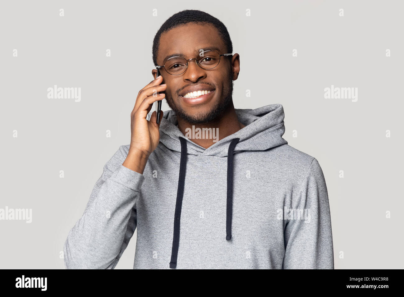 Lächelnd African American Kerl in hoodie Gespräch auf dem Handy Stockfoto