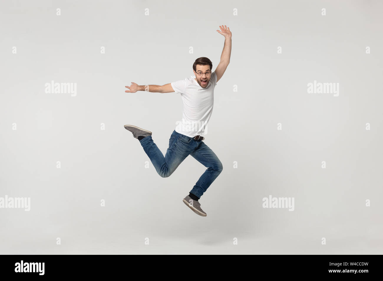 Vivacious Kolleginnen und Blick in die Kamera auf grauem Hintergrund isoliert springen Stockfoto