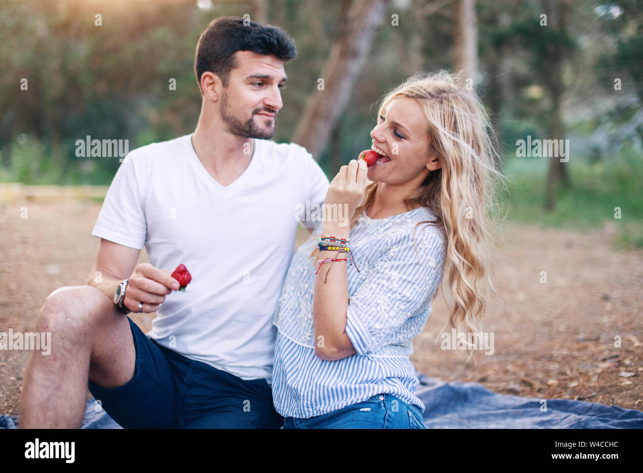 Junges Paar essen Erdbeere auf Picknick in der Natur Stockfoto