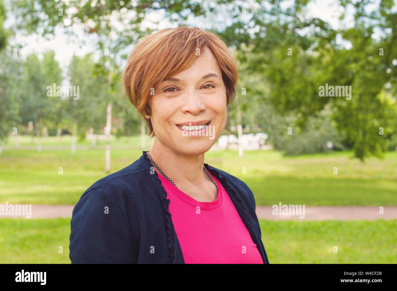 Closeup Portrait von gesunden Lächeln ältere Frau im Freien. Elegante reife rothaarige Frau mit kurzen Haaren lächelnd Stockfoto