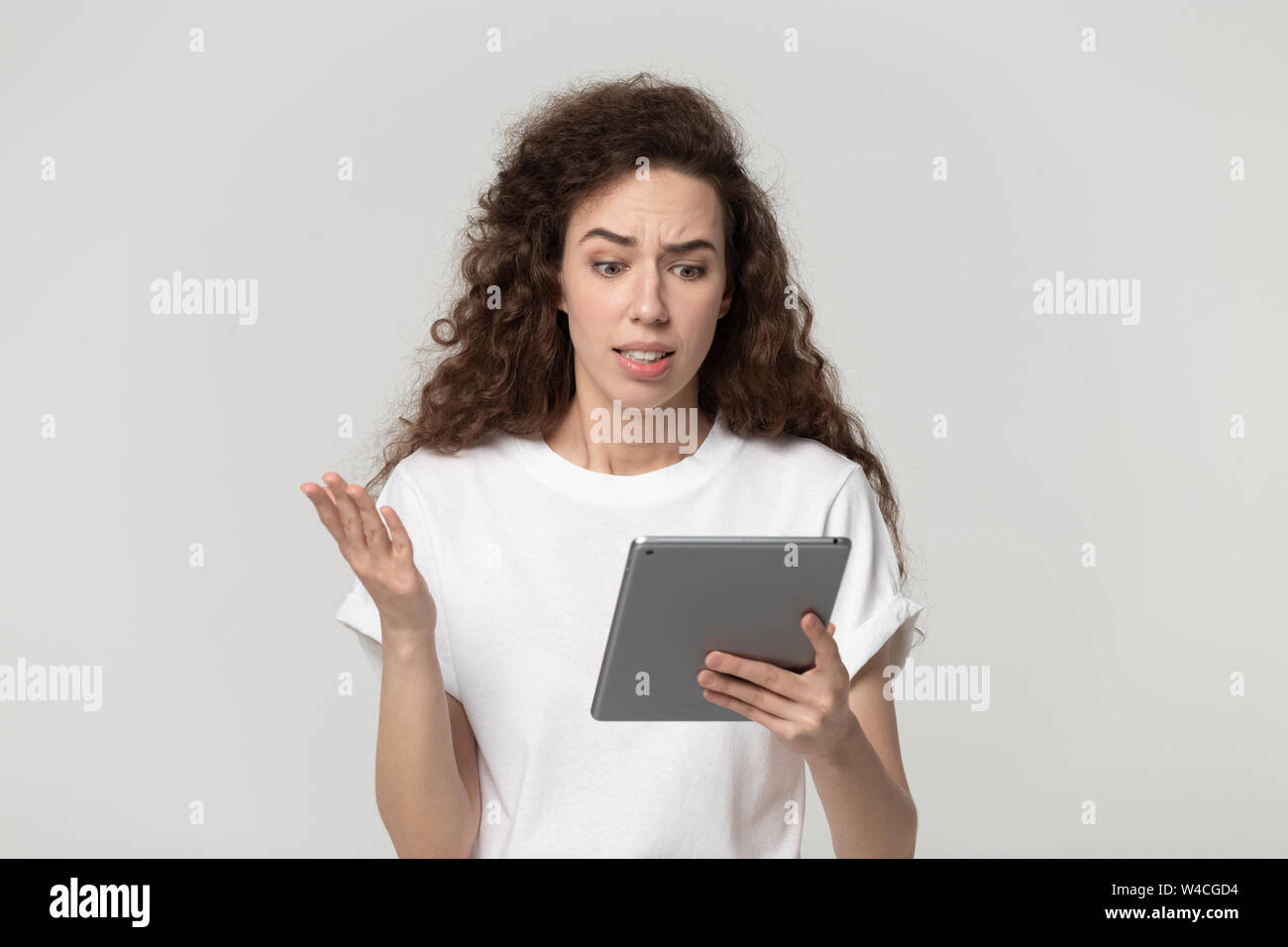 Gereizte Frau an Tablet Bildschirm schaut fühlt sich wütend Studio shot Stockfoto