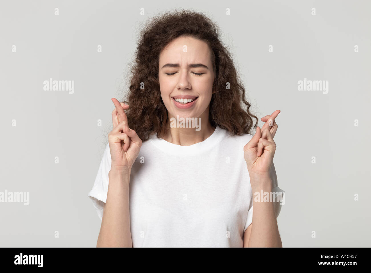 Studio shot Frau mit gekreuzten Fingern fordert viel Glück Stockfoto
