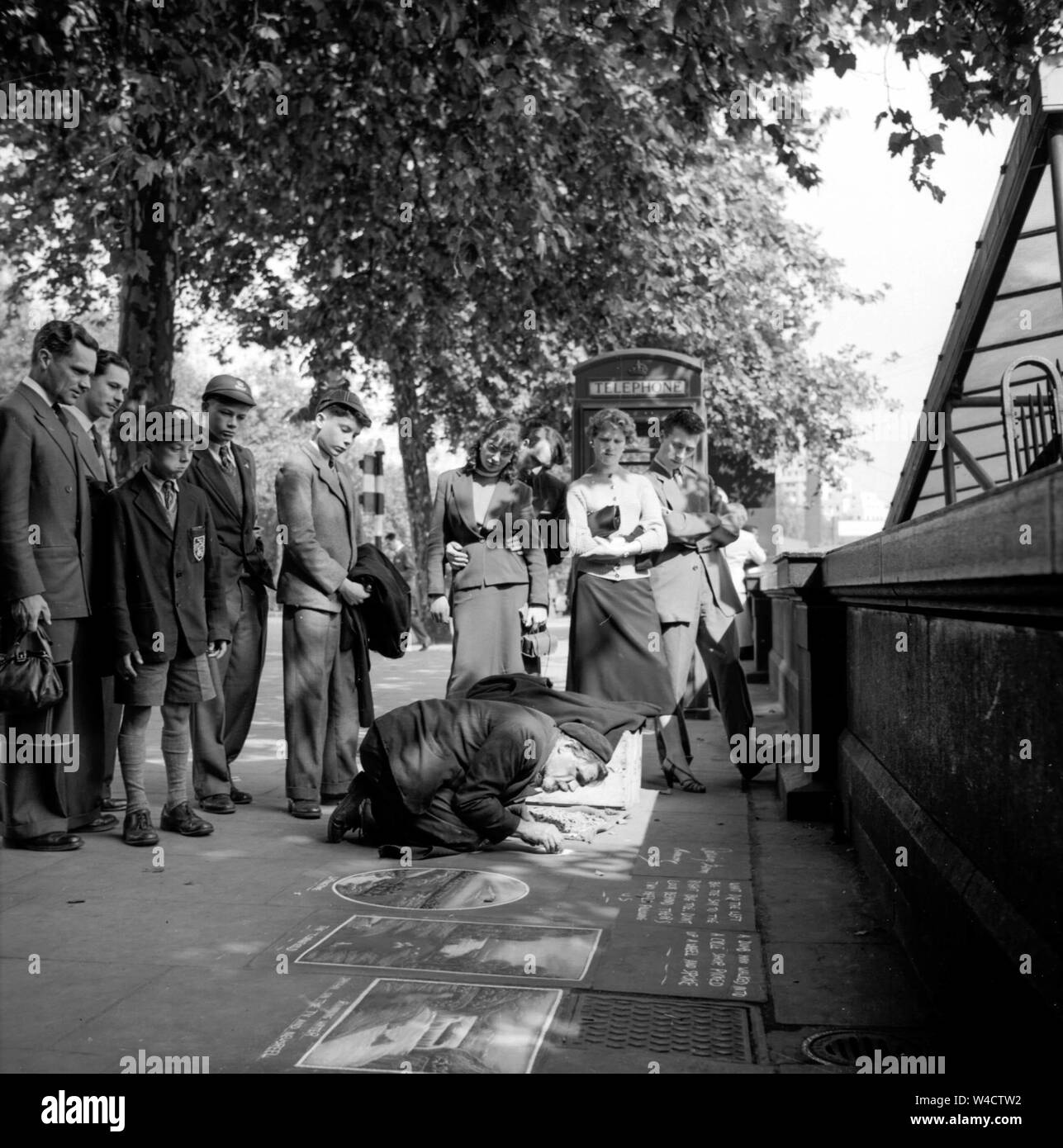 Ein vintage Szene auf dem Bahndamm in London als eine Menschenmenge sammelt runde Pflaster Künstler bei der Arbeit mit seiner Kreide in den 1950er Jahren Stockfoto