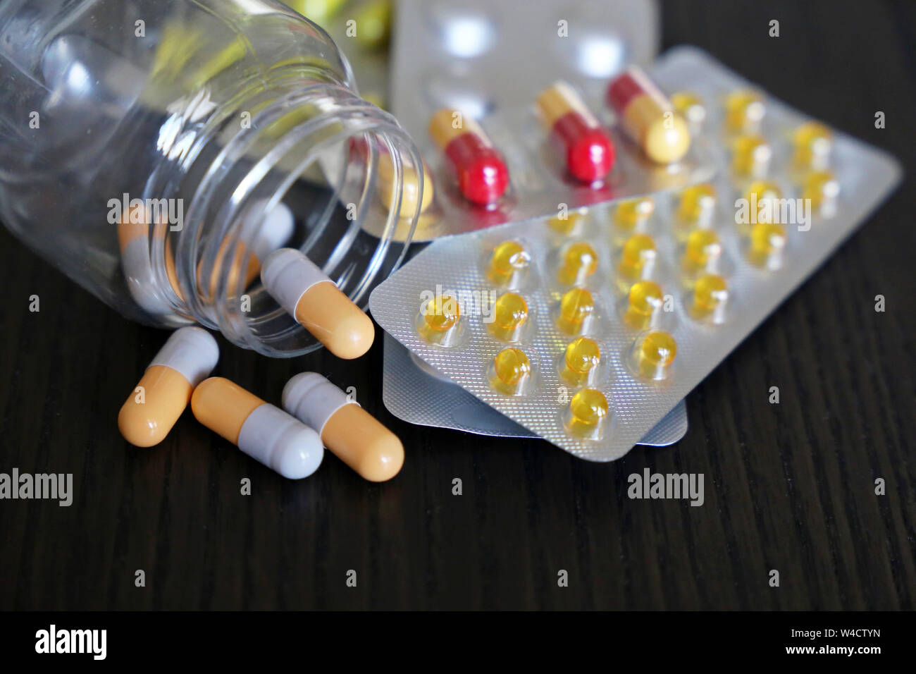 Tabletten in Blisterpackungen und in Kapseln in transparente Flasche auf Vintage dunklen Holztisch. Konzept von Drogen, Antibiotika, Vitamine, Apotheke Stockfoto