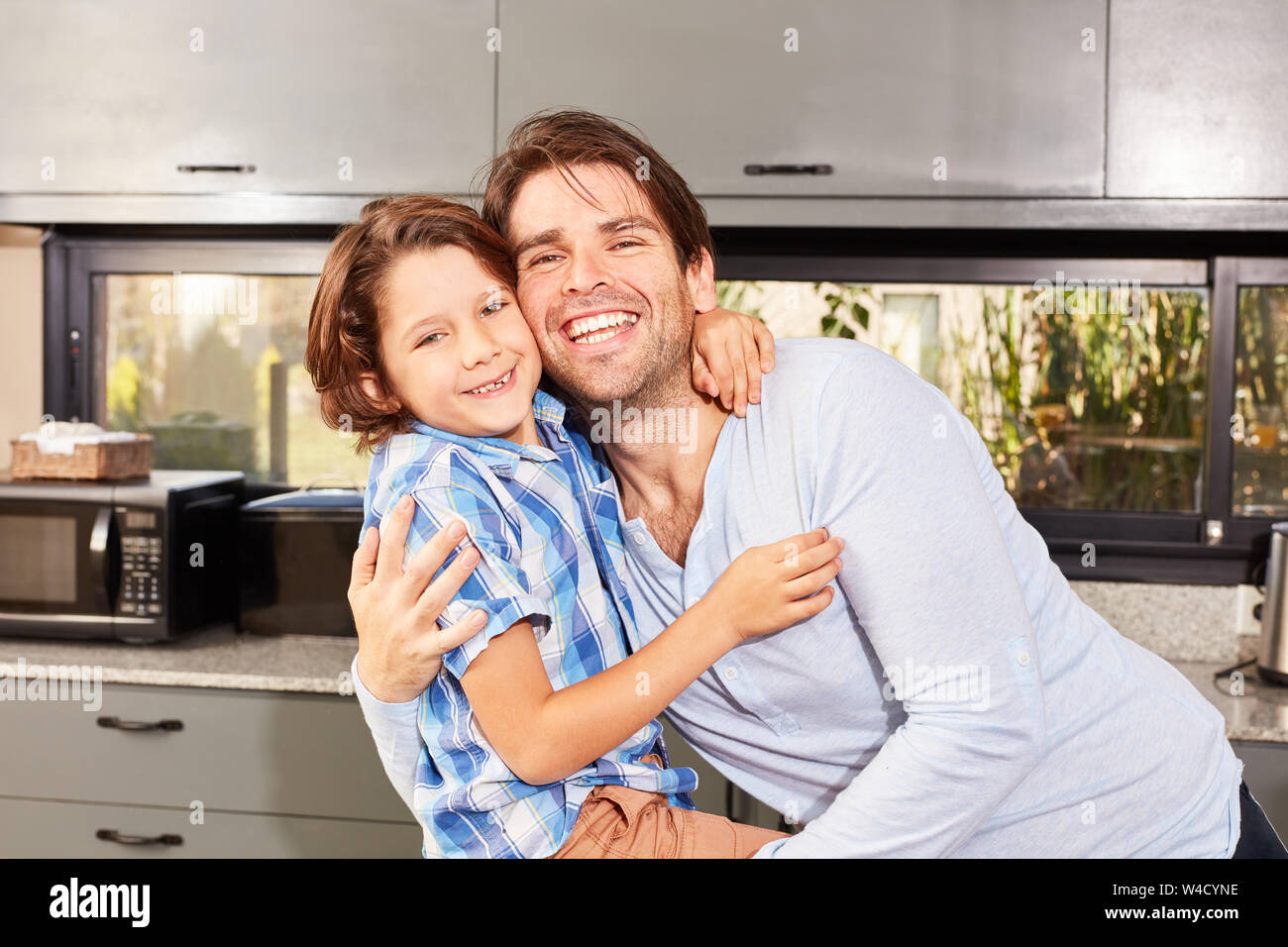 Gerne Alleinerziehende stolz umarmt seinen Sohn in der Küche Stockfoto
