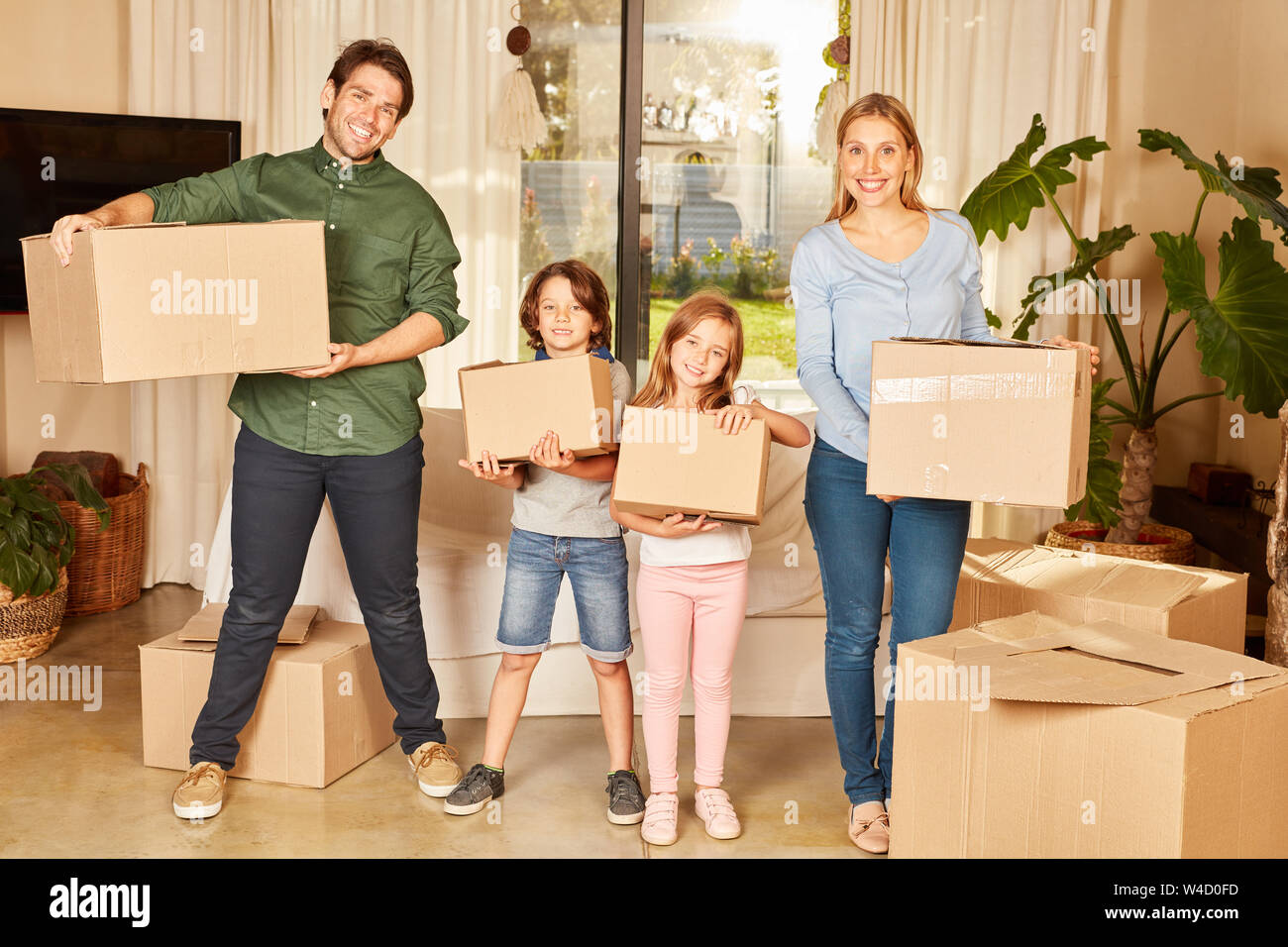 Eltern und zwei Kinder mit Kisten in das neue Haus oder die neue Wohnung Stockfoto