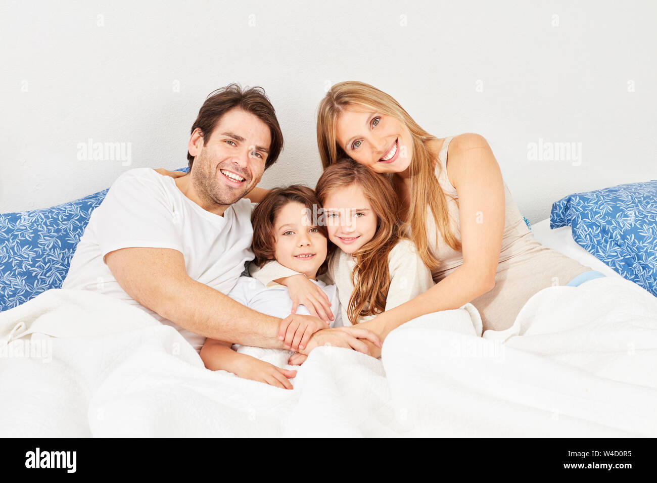 Glückliche Eltern und zwei Kindern kuscheln im Bett im Schlafzimmer Stockfoto