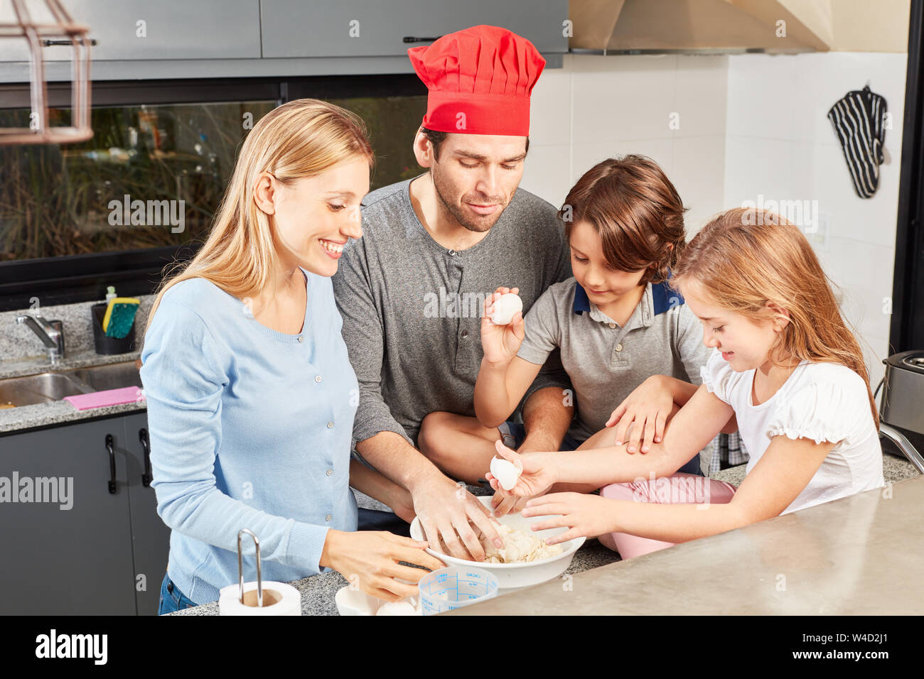 Eltern kneten Teig für ein Brot oder Kuchen mit ihren Kindern Stockfoto