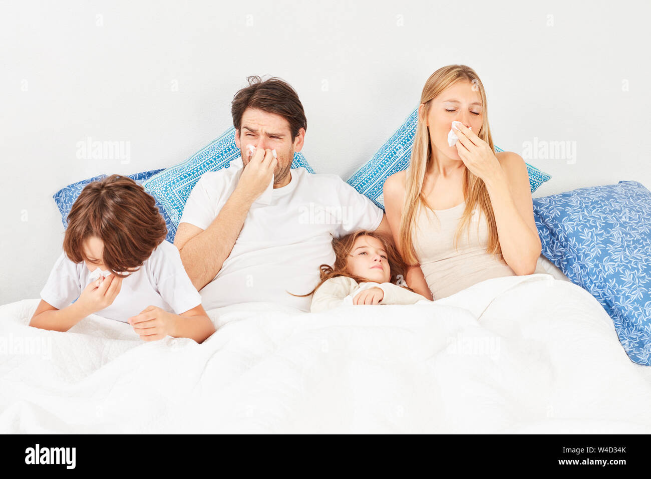 Familie mit zwei Kindern hat die Grippe oder Heuschnupfen und liegt im Bett zusammen Stockfoto