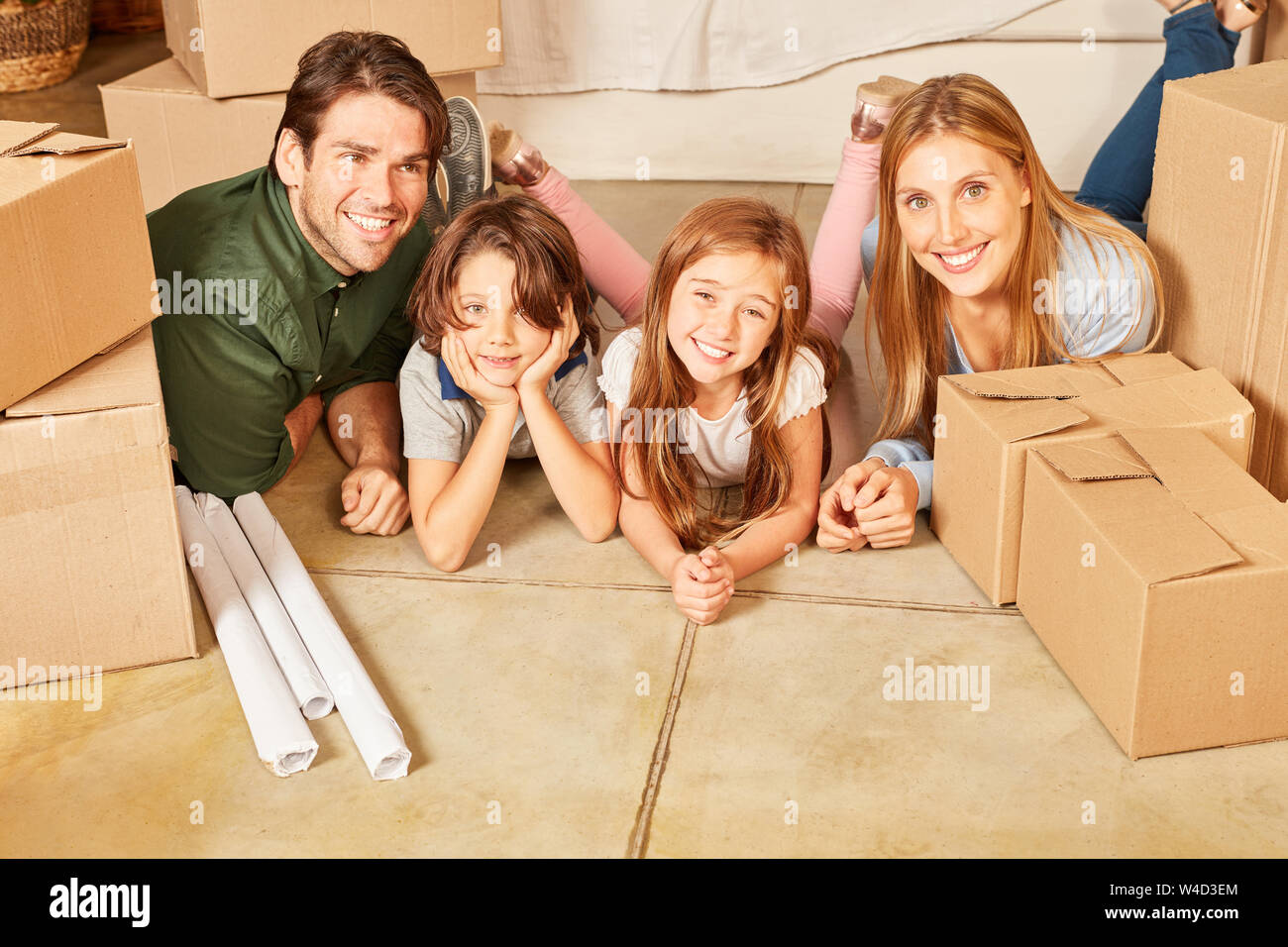 Glückliche Familie mit zwei Kindern im neuen Haus zwischen beweglichen Kästen Stockfoto