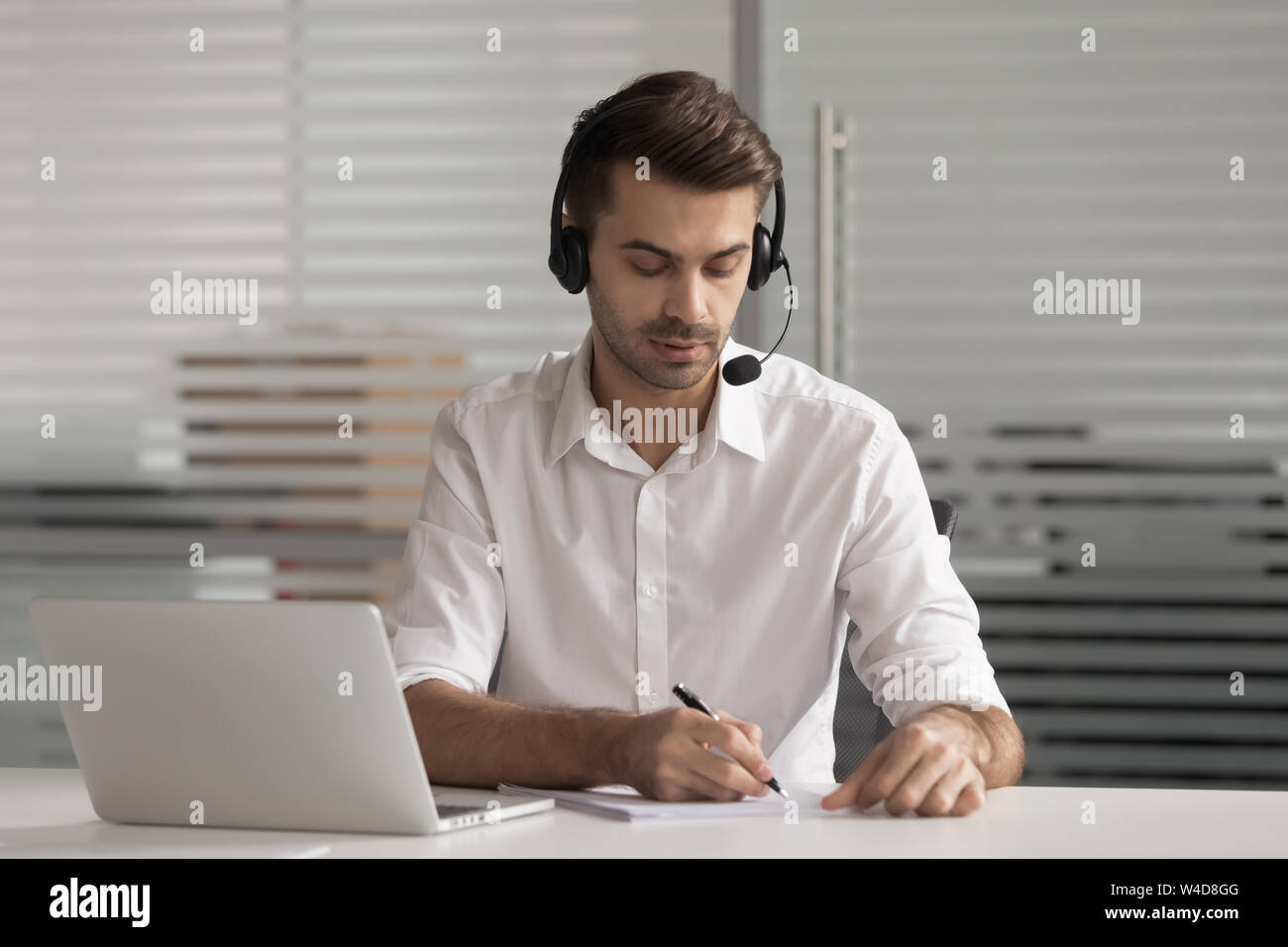 Ernsthafte Customer Support Agent tragen Headset schreiben Sie Notizen machen videocall Stockfoto