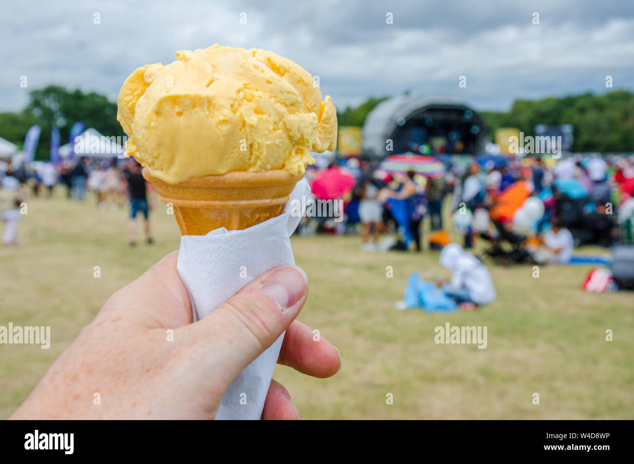 Eine männliche Hand mit einem Kegel von Eis in ein Feld auf einem Festival. Stockfoto