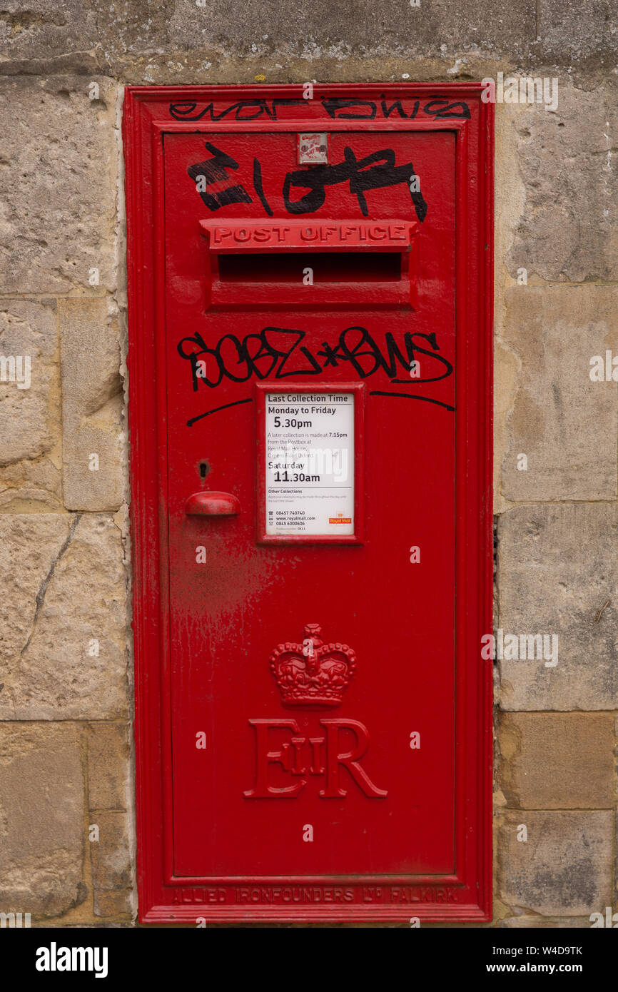 Ein vandalized roten Briefkasten, innerhalb einer Steinmauer in Oxford, England Stockfoto