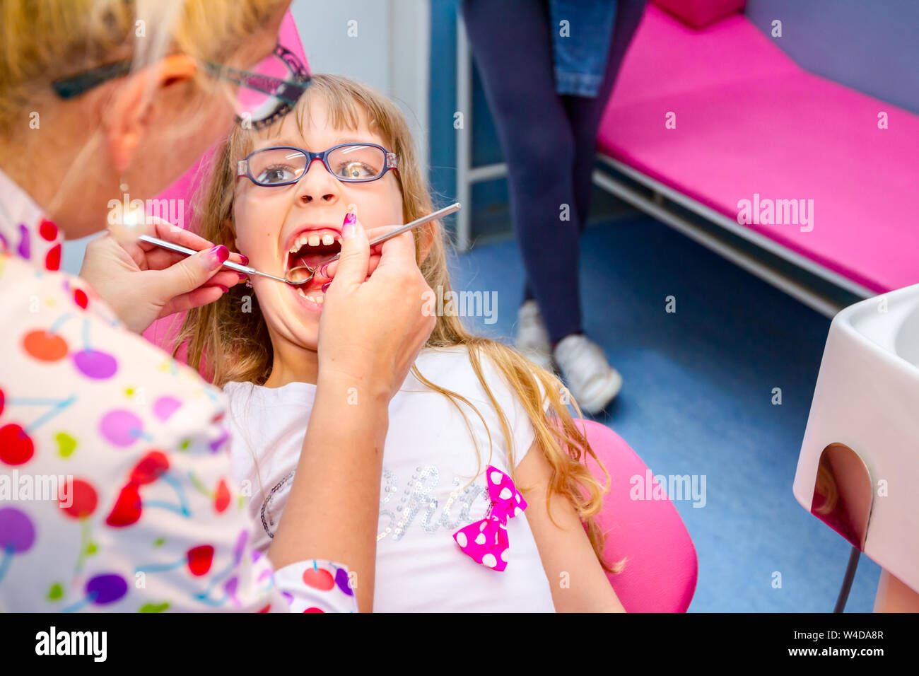 Portrait von süßen kleinen Mädchen mit offenen Mund, Gläser und unbeschwerten Ausdruck auf ihrem Gesicht während der zahnmedizinischen prüfen. Stockfoto