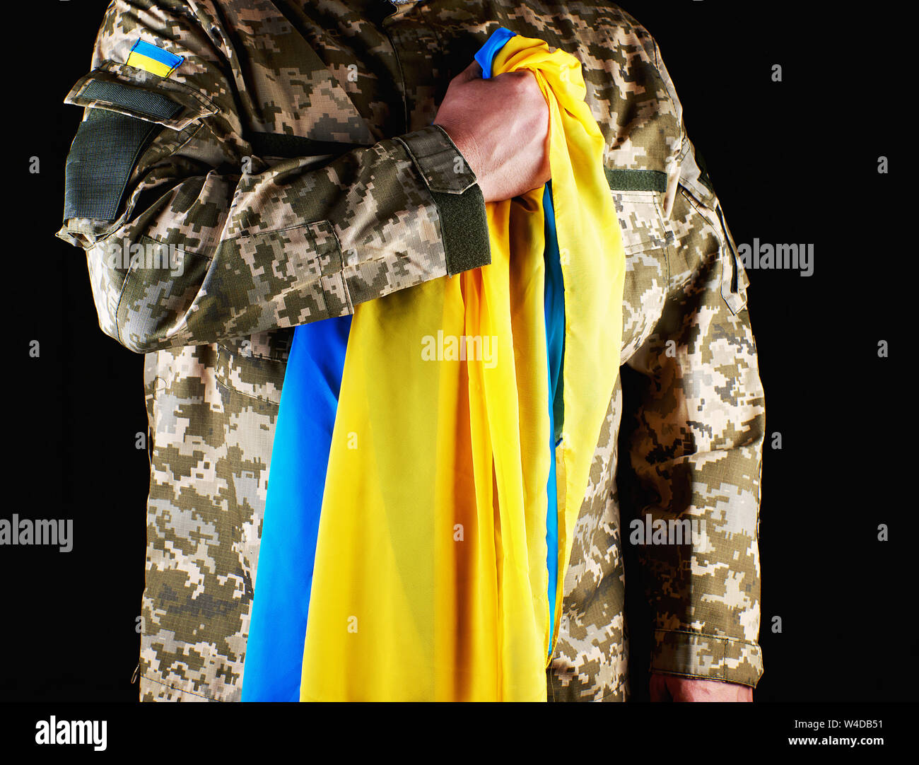 Ukrainische Soldaten hält in seiner Hand das gelb-blaue Flagge des Staates, er presste seine Hand an seine Brust, Konzept der Erinnerung an die toten Soldaten Stockfoto