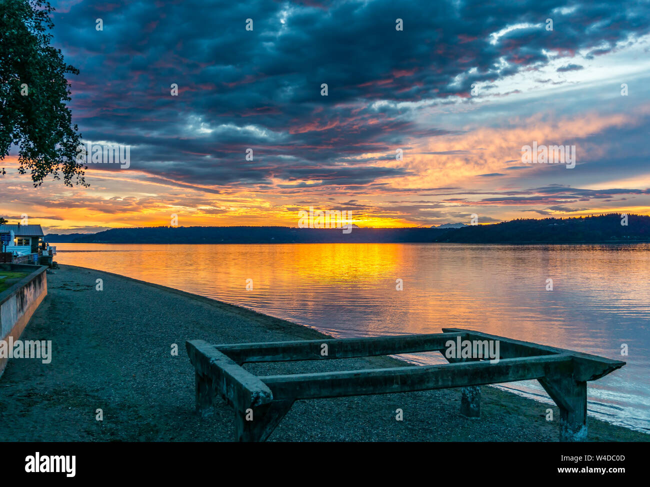 Die Wolken hängen am Himmel, wie die Sonne hinter den Olympic Mountains im Armaturenbrett, Washington. Stockfoto