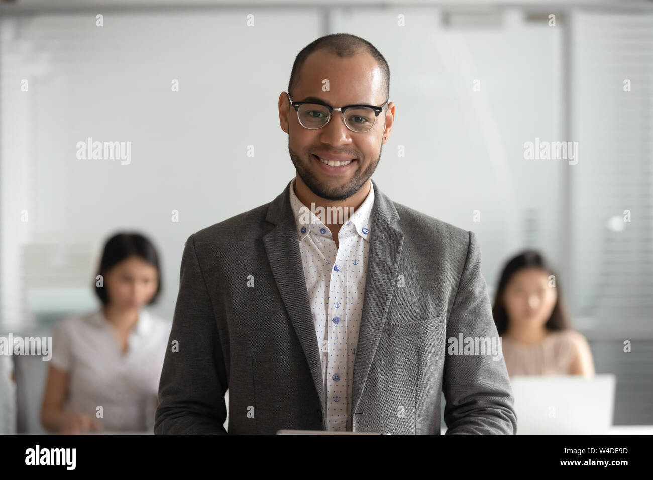 Lächelnd afrikanischen Geschäftsmann in Anzug bei Kamera schaut im Büro Stockfoto