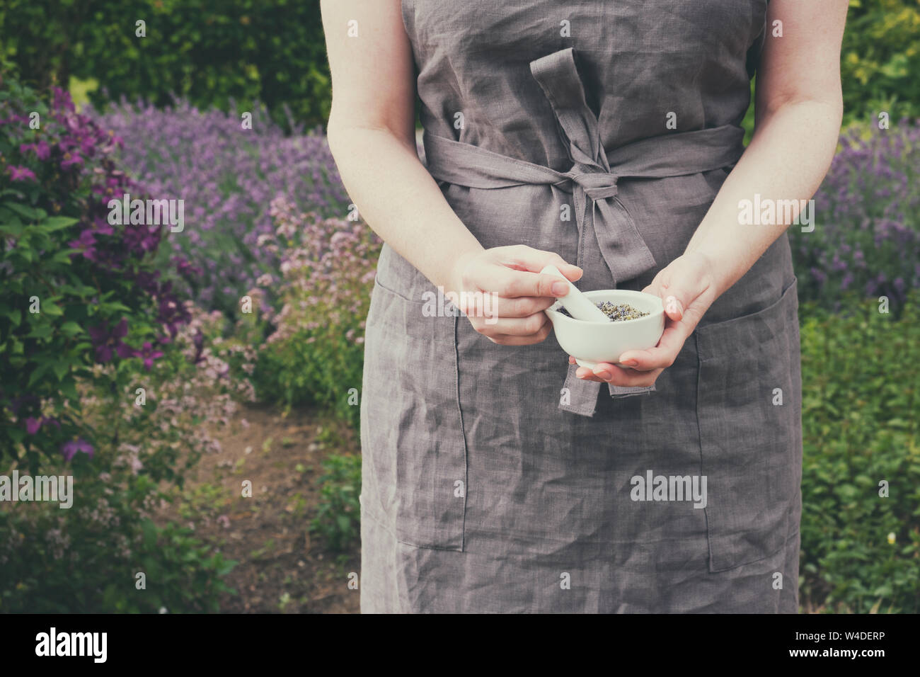 Frau in ihrer Hände halten ein Mörtel von heilenden Kräutern. Herbalist sammelt Heilpflanzen im Garten. Stockfoto