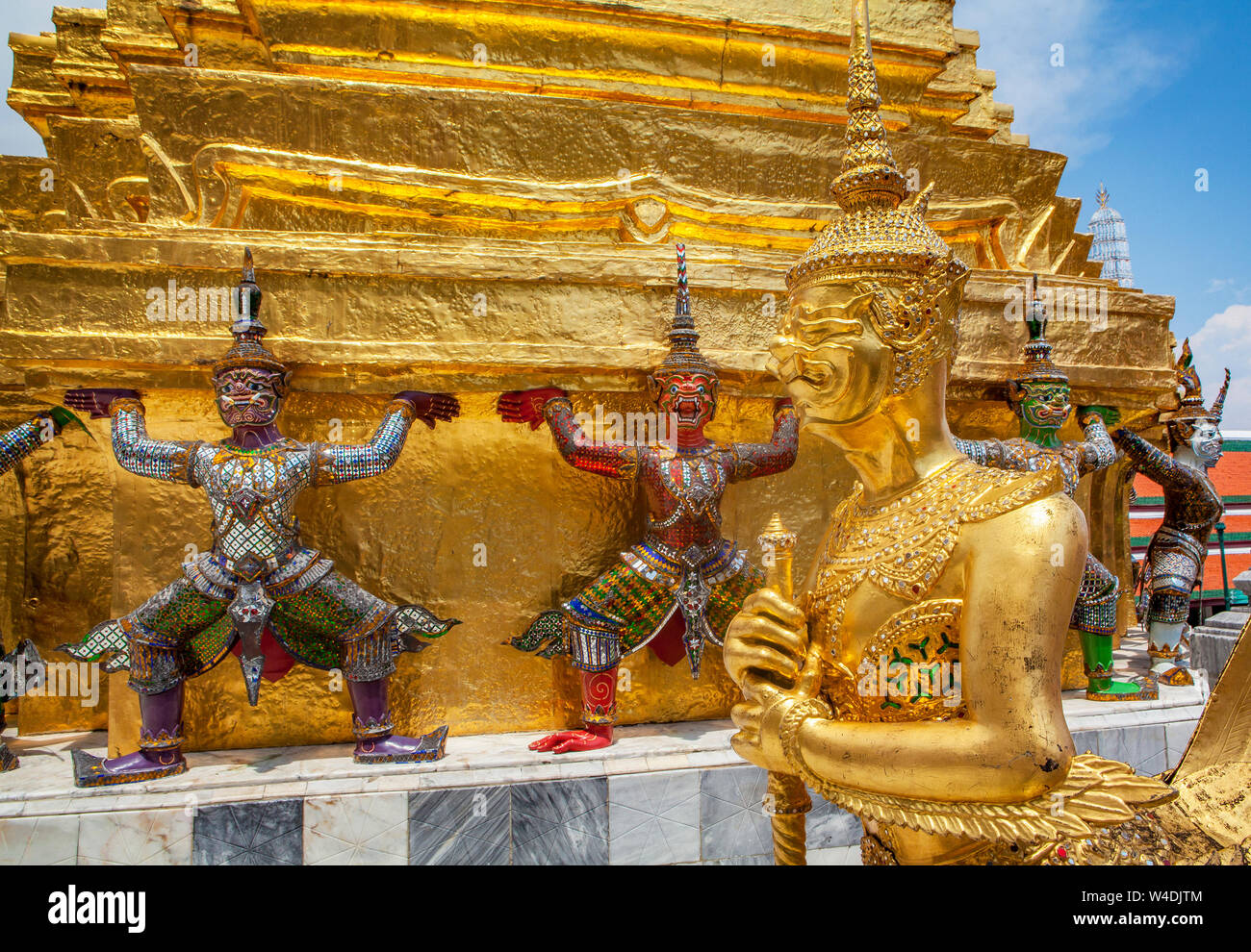 Garuda und Yaksha mythische Krieger Statuen bewachen die vergoldeten Chedi in der Nähe der Tempel des Smaragd Buddha im Grand Palace in Bangkok, Thailand. Stockfoto