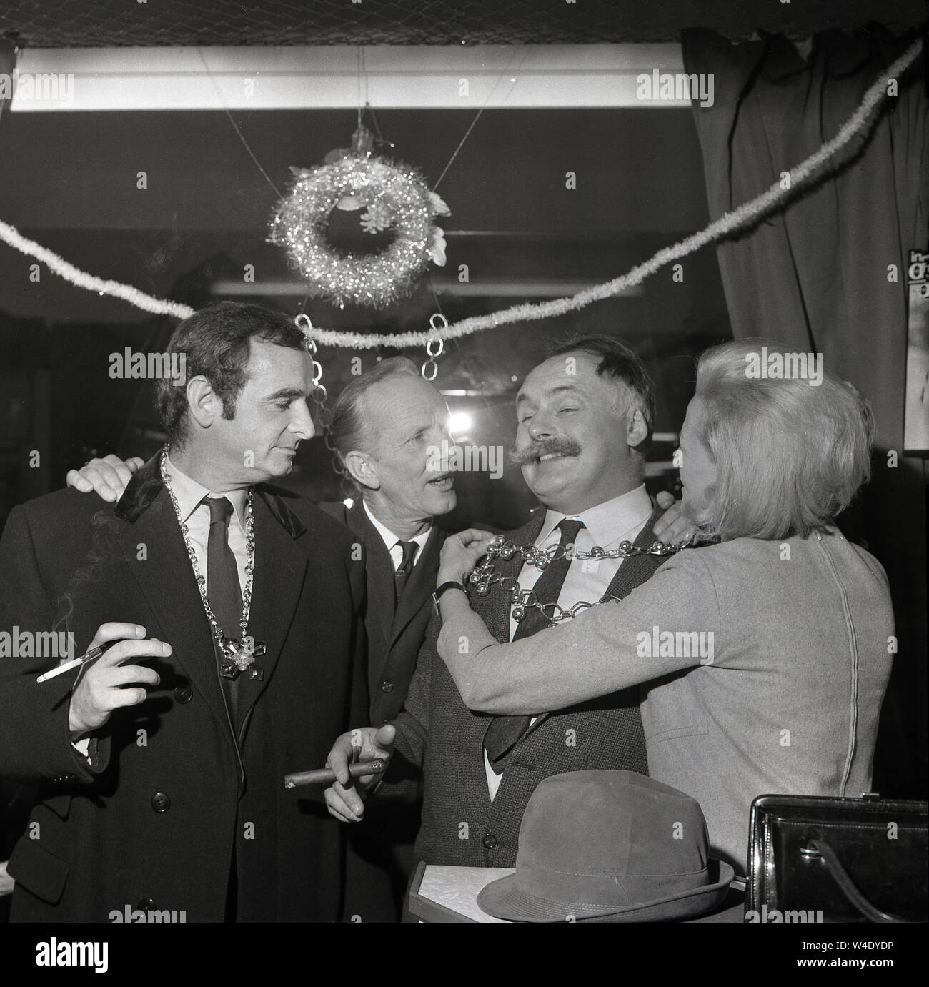 1960, historische, Comedy Stars der Radio panel Spiel, 'hat das Team Denken" hier gesehen auf einer Party mit Jimmy Edwards, der Schöpfer des Spiels auf der rechten, Rauchen eine große Zigarre, London, England, UK. Eine britische Komödie Schriftsteller und Schauspieler, Edwards war berühmt für seine langen 'Lenker' Schnurrbart. Die beliebten panel Spiel, eine Parodie auf "Fragen" wurde für Lachen gespielt und lief seit fast zwanzig Jahren. Stockfoto