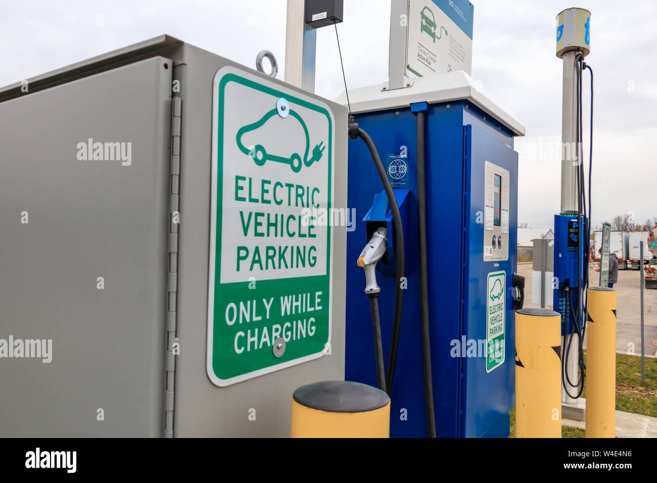 Elektrische Fahrzeug parken - Nur während des Ladevorgangs' Zeichen und Stecker/Leistungsteil im Hintergrund. Stockfoto