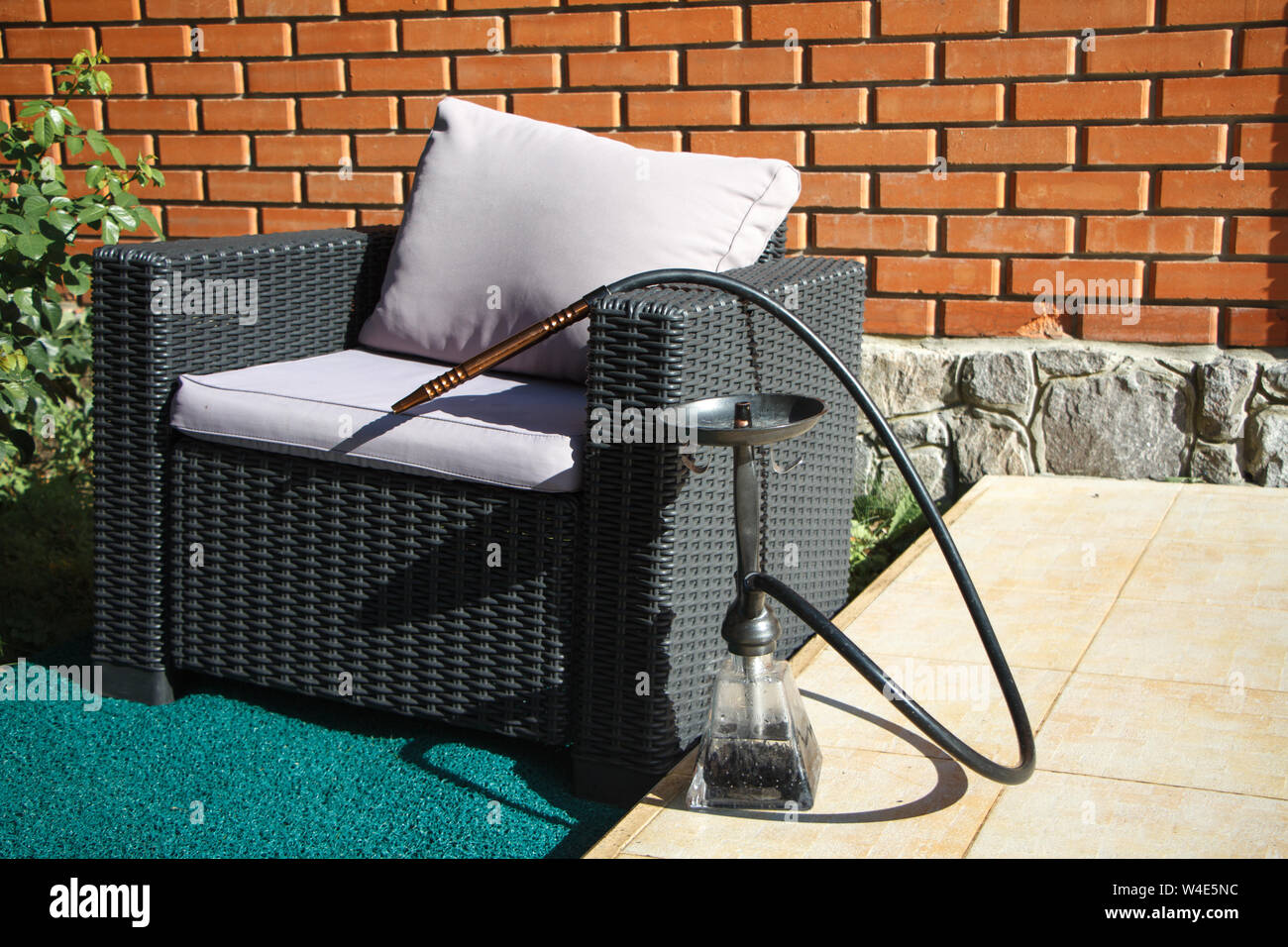 Schwarze Korbsessel mit grau Kissen und Shisha bereit für das Rauchen sind im Sommer auf der Terrasse, Copyspace Stockfoto