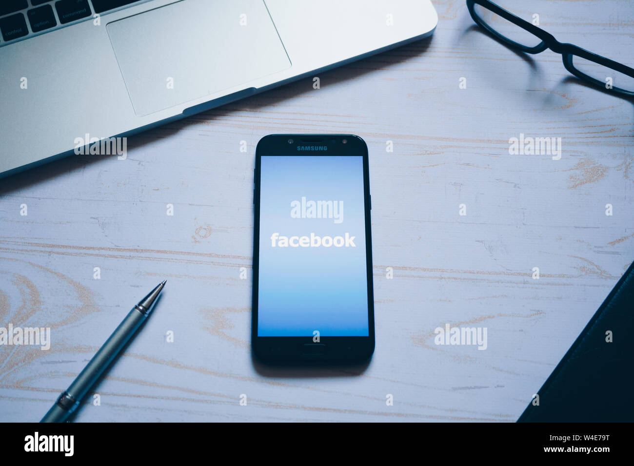 Nizhyn, Ukraine/Juli -16-2019: Facebook App Logo auf dem Bildschirm des modernen Smartphone. Flach. Laptop, Gläser, Notizbuch und Stift für den Hintergrund. Soziale Stockfoto