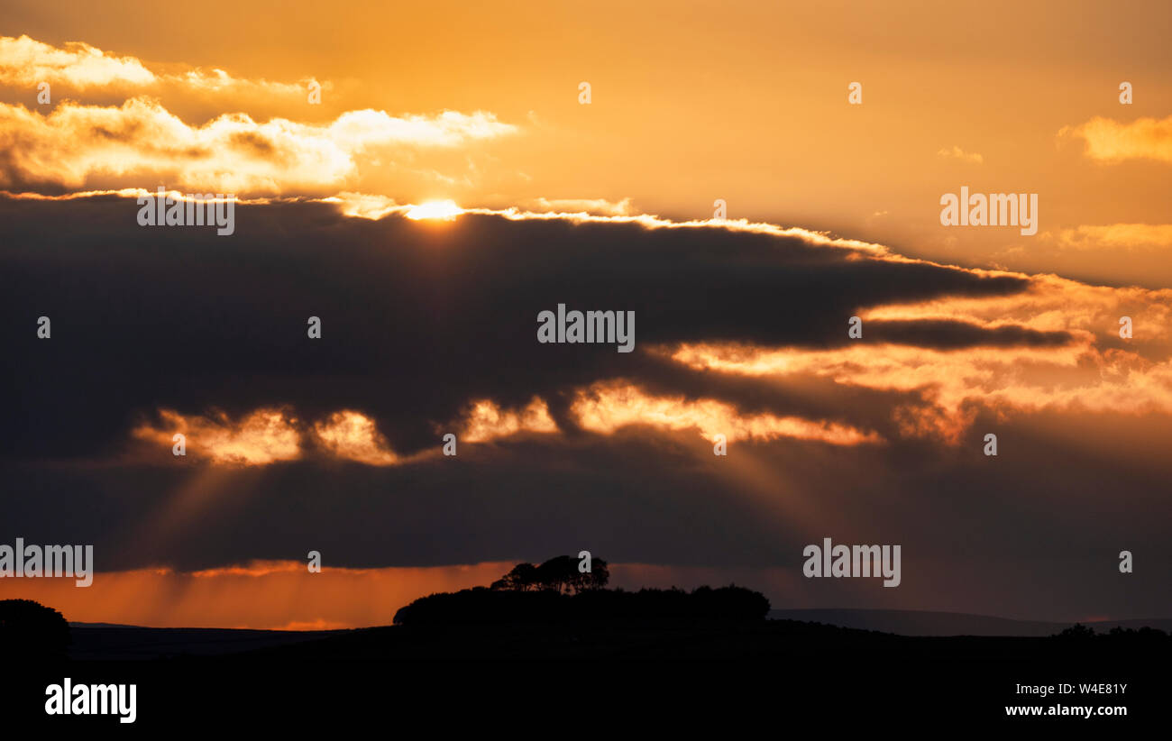 Wetter in Großbritannien: Spektakuläre moody Sonnenuntergang über Minning niedrigen Hügel historischen England Monument mit einem chambered Grab & zwei Schüssel schubkarren von harboro Felsen, Peak District, UK gesehen Stockfoto