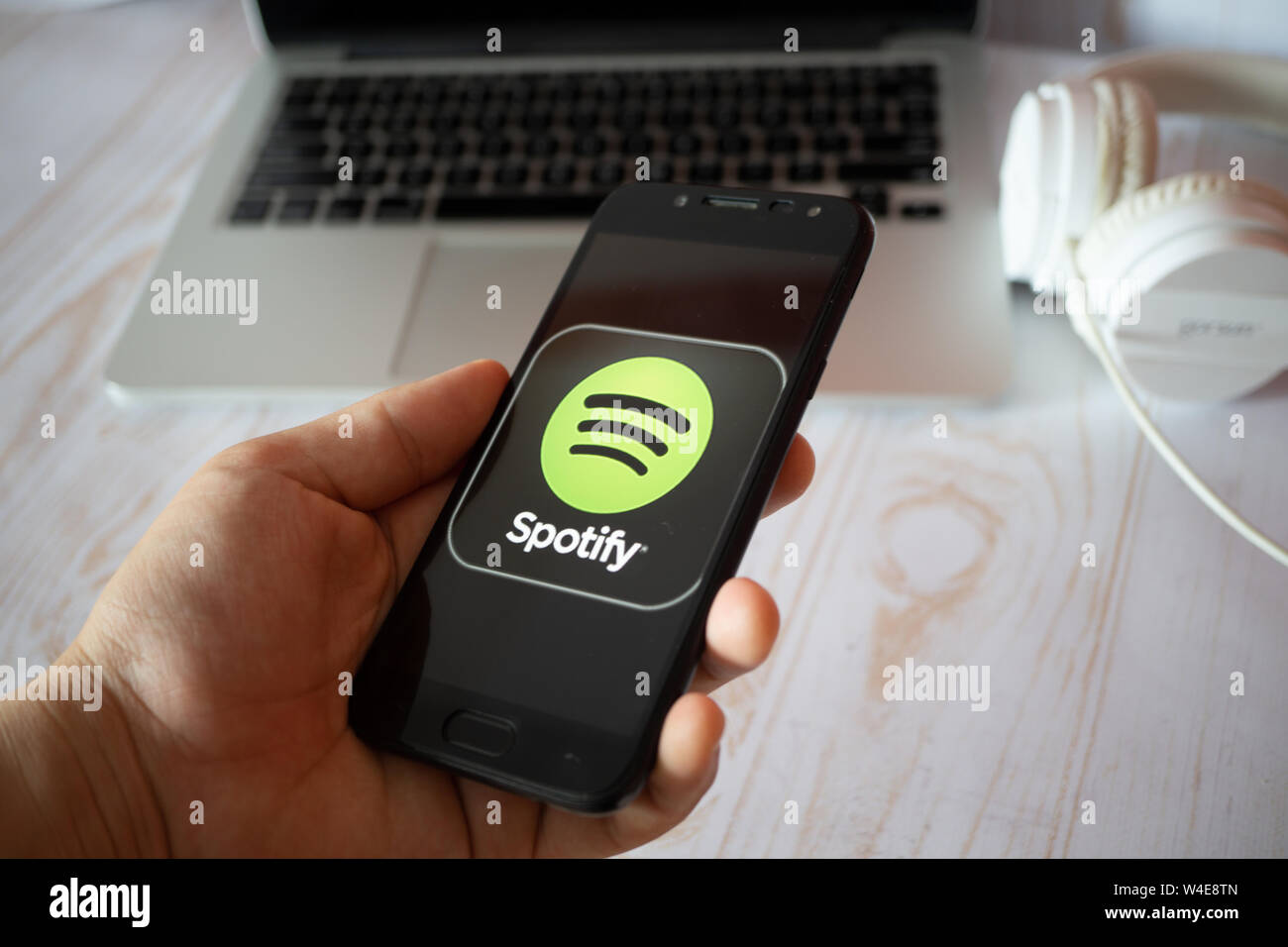 Nizhyn, Ukraine/Juli -16-2019: junger Mann in Schwarz suite halten Smartphone und Spotify app verwenden. Social Media und körperschaftlichen Konzept. Stockfoto