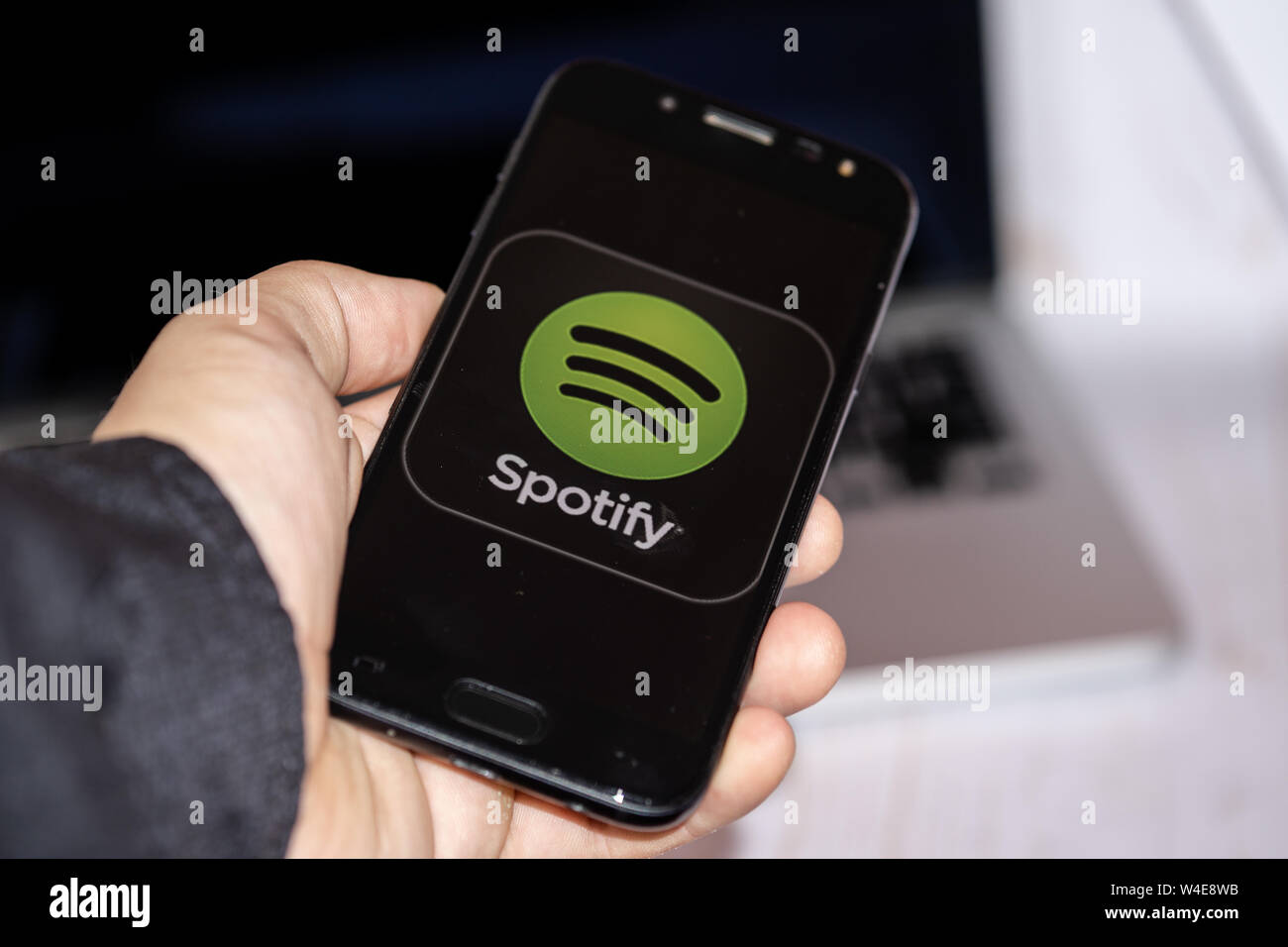 Nizhyn, Ukraine/Juli -16-2019: junge Vertreter der Mann in Schwarz suite halten Smartphone und Spotify app verwenden. Social Media und körperschaftlichen Konzept. Stockfoto