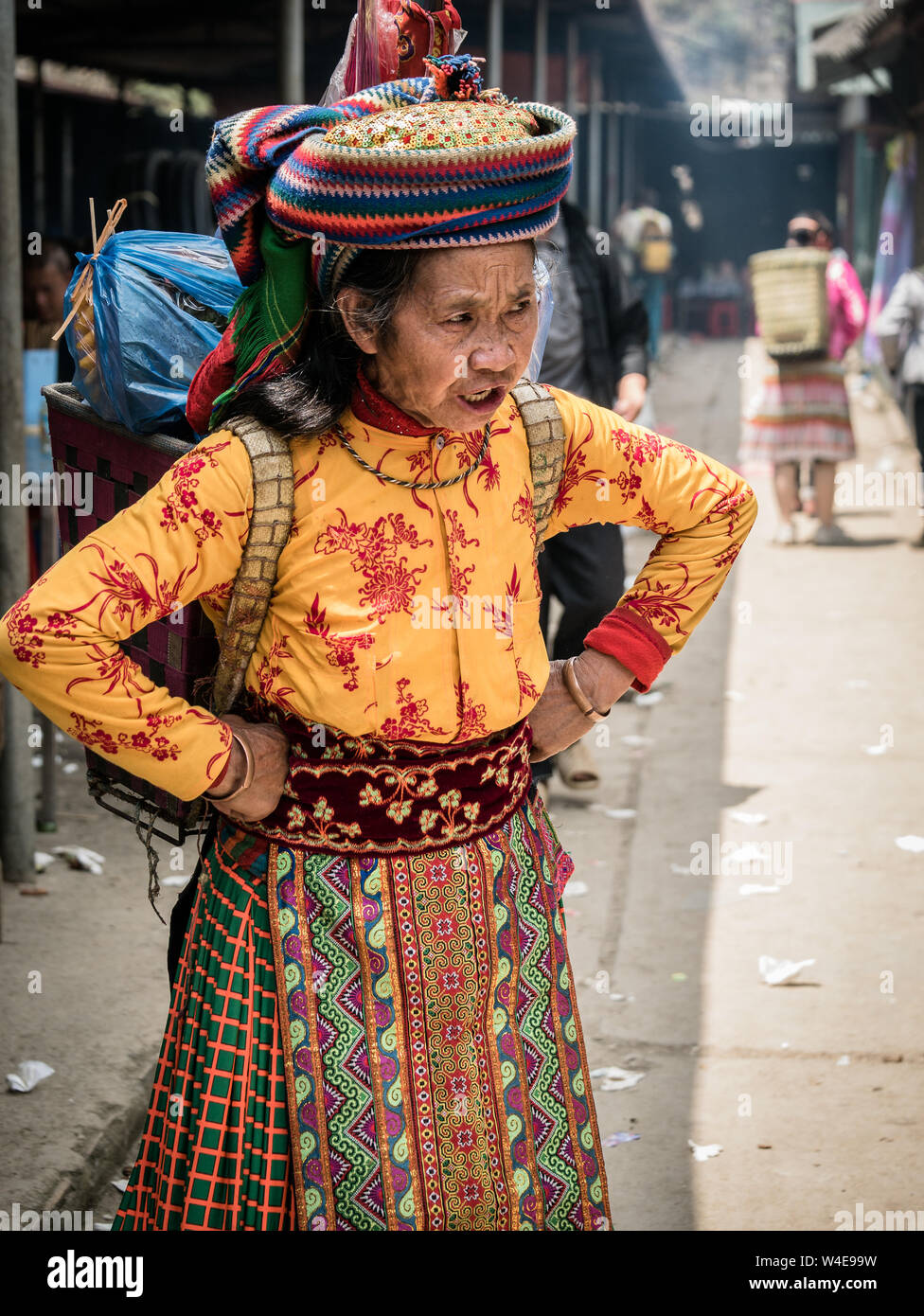 Dong Van, Vietnam - 05/26/2019: Alte vietnamesische Frau mit Korb auf dem Rücken in der traditionellen bunten Kleid der ethnischen Minderheit an Dong Van Sonntag Markt Stockfoto