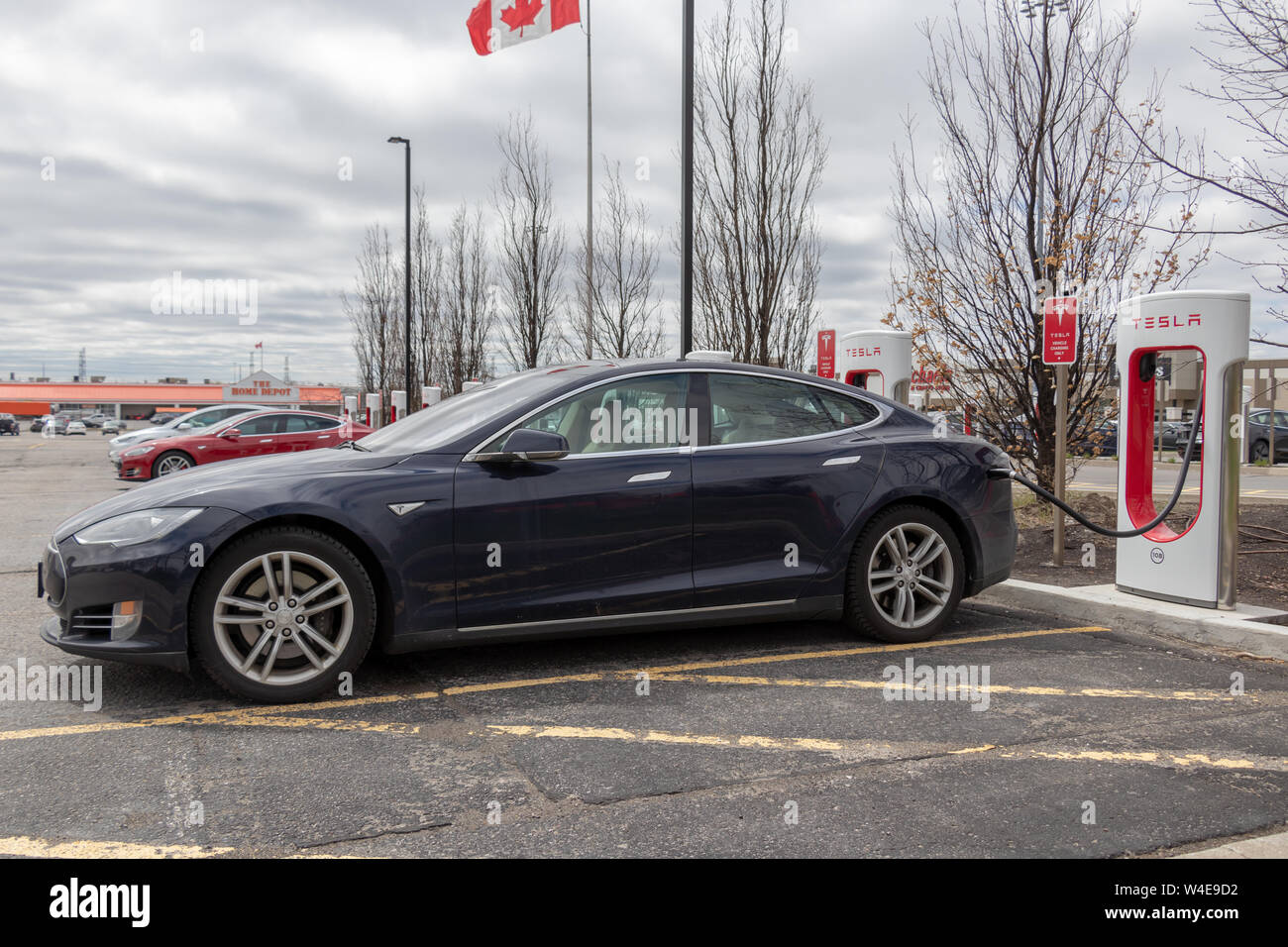 Blau Tesla Model S bei Tesla Kompressor in Markham, mit Model S, Modell X und Kanadischen Flagge im Hintergrund geparkt. Stockfoto