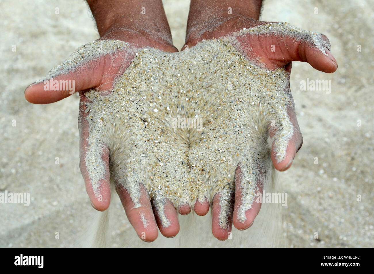 DNA-Mensch ein Mann und eine Frau das Hocken auf Tybee Strand Sand durch ihre Hände gegossen haben. Stockfoto