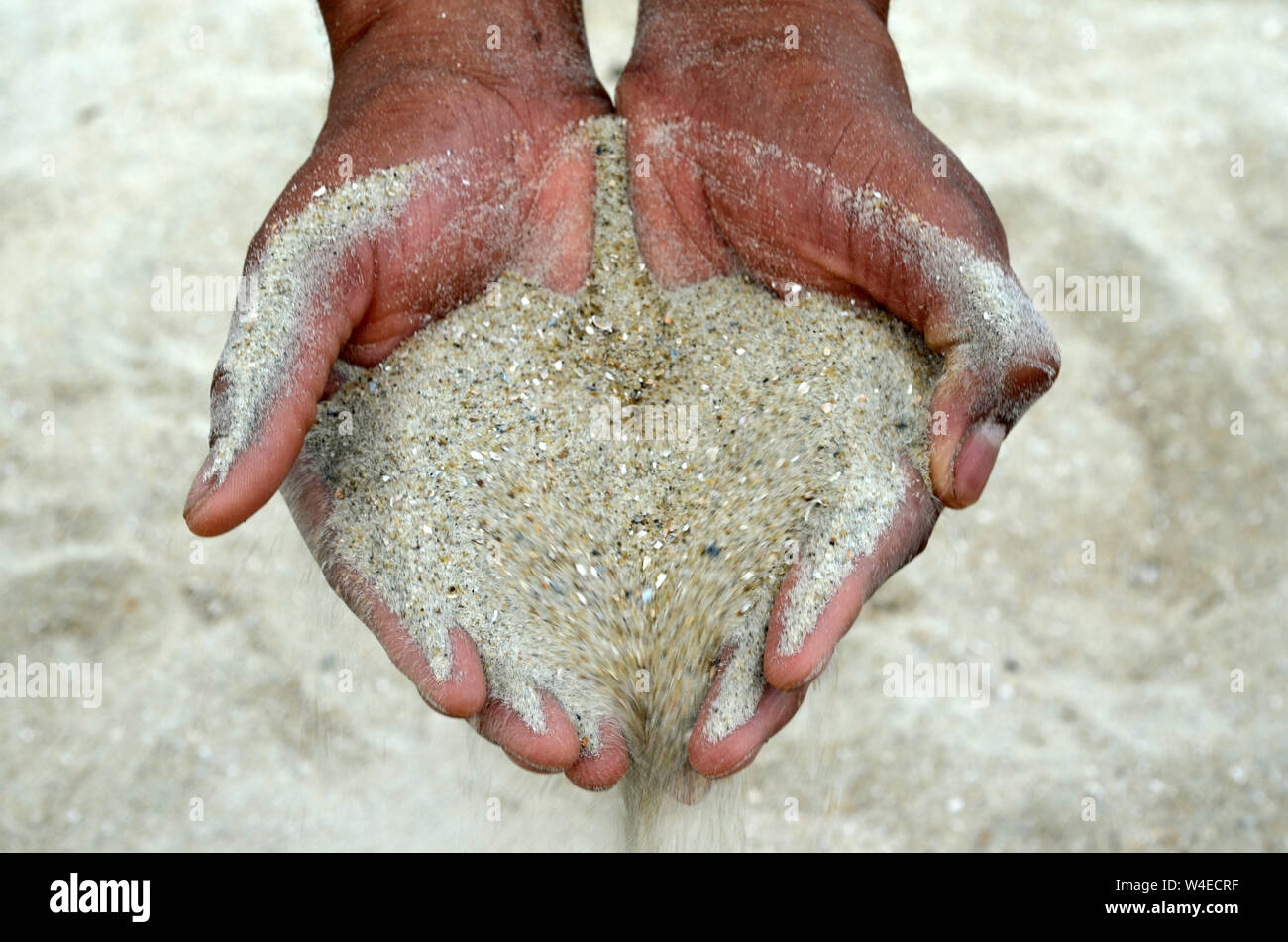 DNA-Mensch ein Mann und eine Frau das Hocken auf Tybee Strand Sand durch ihre Hände gegossen haben. Stockfoto