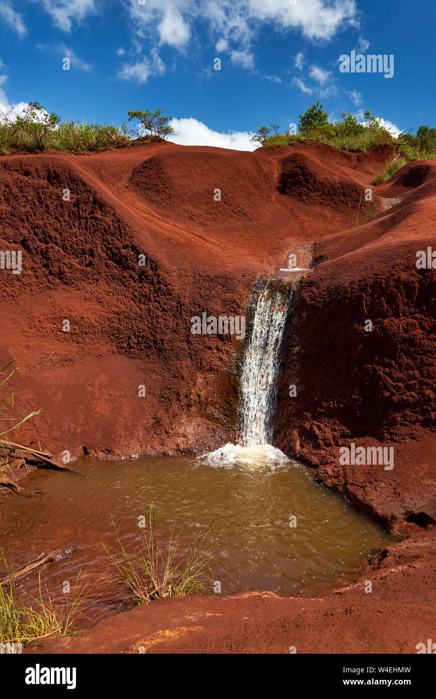 Wasserfall und Pool aus einem kleinen Dampffluss über robuste Red Rock Gelände in der Nähe von Waimea Canyon auf Kauai, Hawaii. Stockfoto