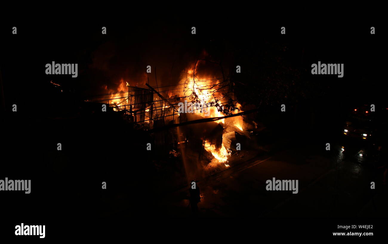 Feuerwehrmann versuchte ein Feuer, das in der Nacht geschehen. Löschfahrzeuge im Hintergrund. sehr dunklen Hintergrund. Stockfoto