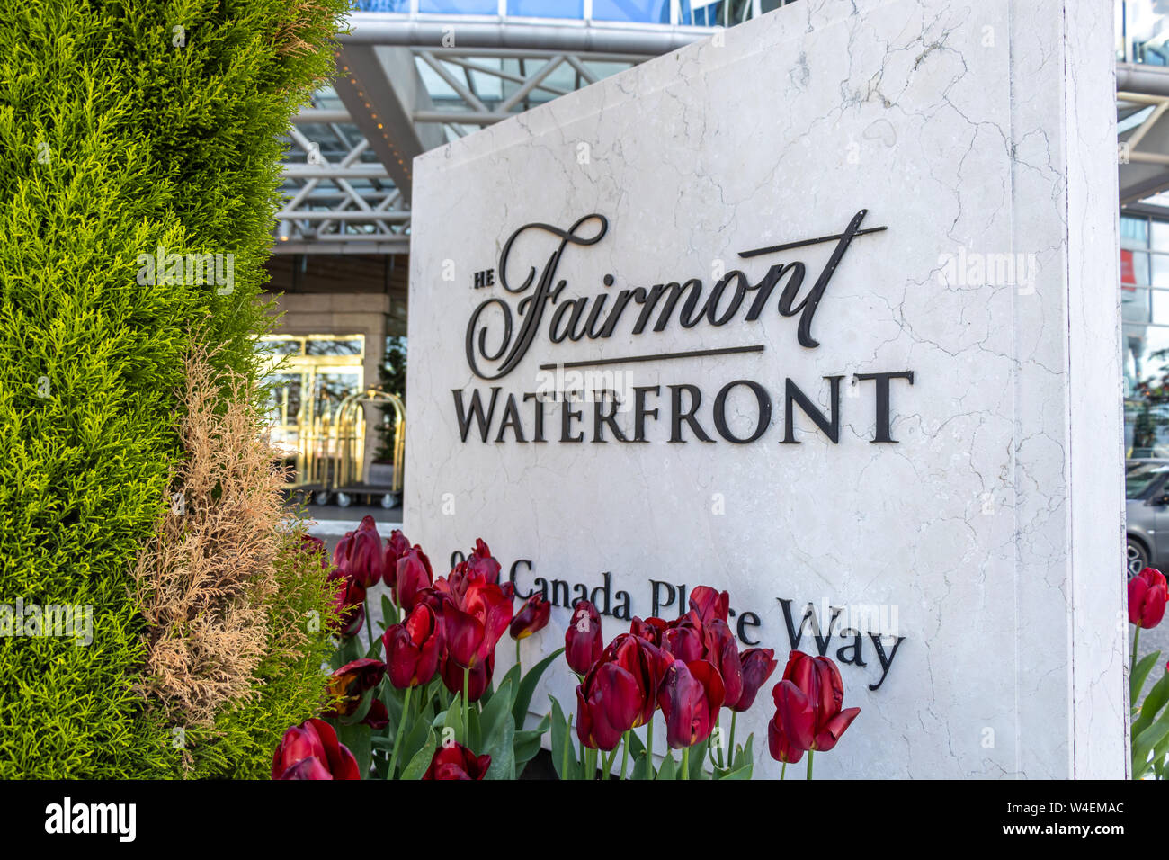 Schild vor dem Fairmont Waterfront Hotel am Hafen von Vancouver, wenn Frühlingsblumen blühen. Stockfoto