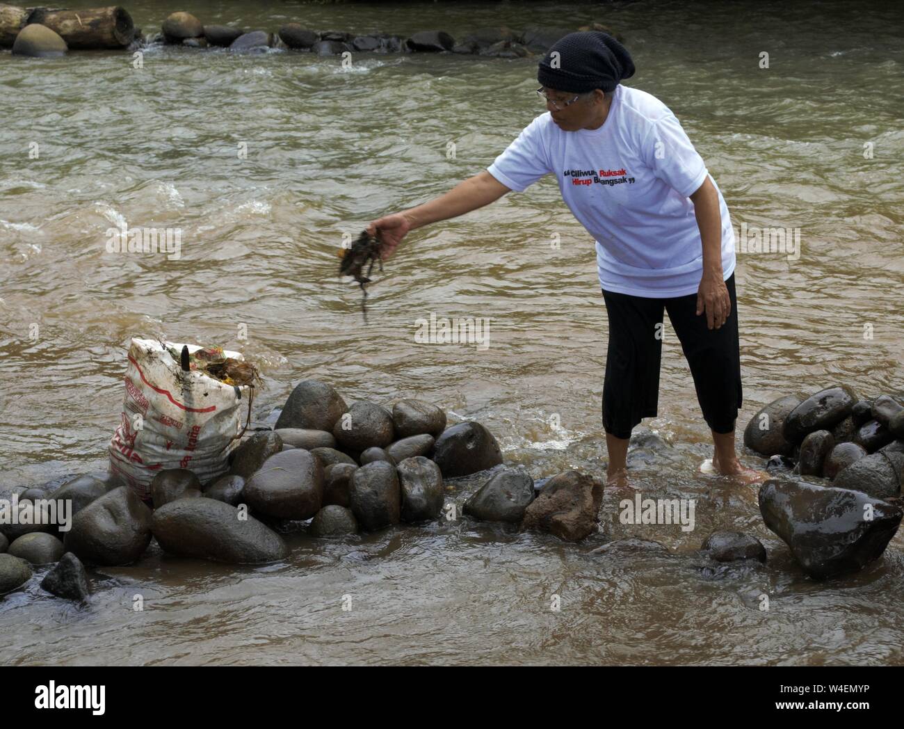 Bogor, West Java, Indonesien - Juli 2019: Ein älterer Frauen nimmt Müll aus Ciliwung Fluß. Stockfoto