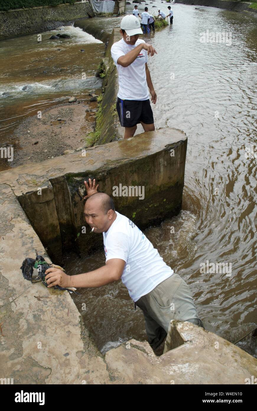Ein Mann hebt den Abfall in kleinen Damm in einem Fluss. Stockfoto