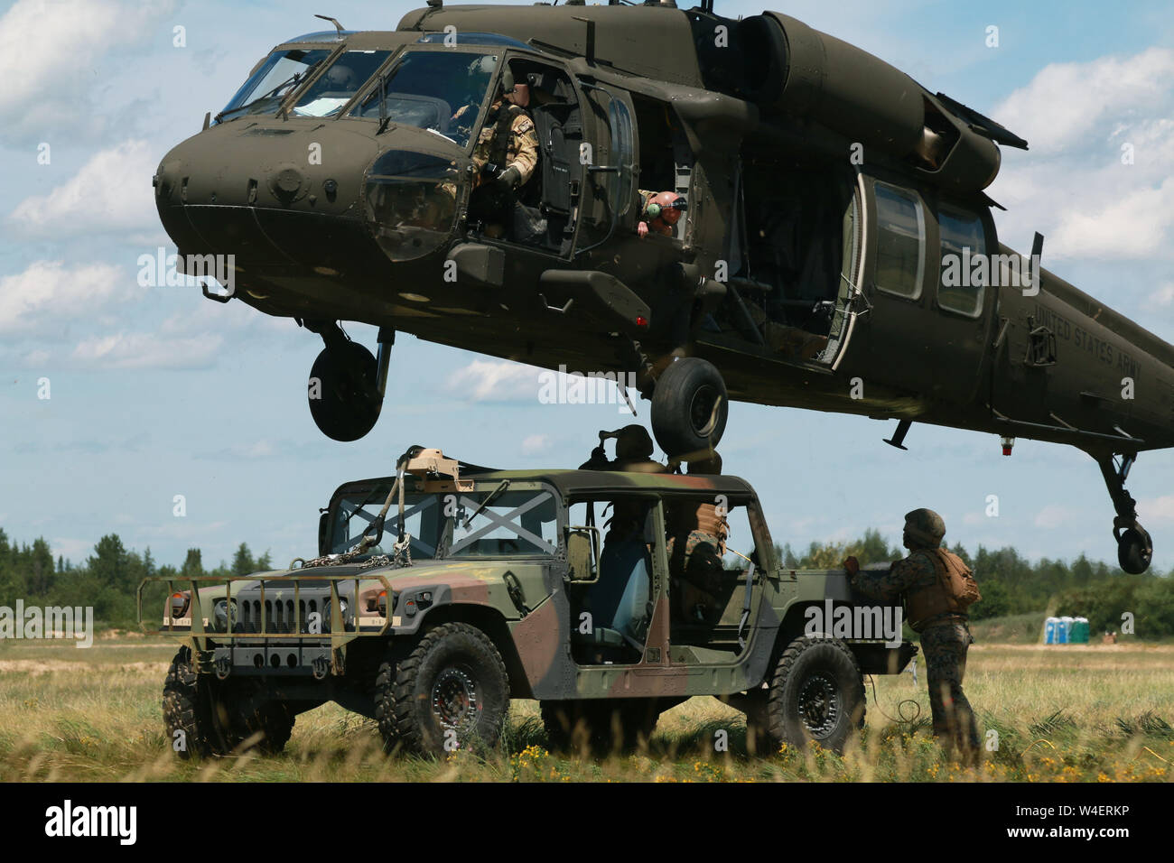 Mitglieder der Alpha Company, 1. Der 158. Assault Helicopter Bataillon durchführen Schlinge Last während Northern Strike 19 auf Lager Äsche, Michigan, 21. Juli 2019. Northern Strike19 ist ein National Guard Bureau - geförderte Übung vereint service Mitglied aus mehr als 20 Staaten, mehrere Service Niederlassungen und zahlreichen Koalition Ländern während der letzten zwei Wochen im Juli 2019 im Camp Äsche gemeinsame Manöver Training Center und die alpena Combat Readiness Training Center. (U.S. Army National Guard Foto von Armee Sgt. Priscilla Desormeaux/Freigegeben) (Foto 7/8-Fach zu markieren. Stockfoto