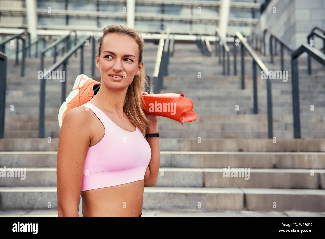 Keine Grenzen glückliche Frau im Sport Kleidung ihr Bein Prothese halten und Lächeln beim Stehen im Freien. Behinderten Sport Konzept. Motivation. Gesunder Lebensstil Stockfoto