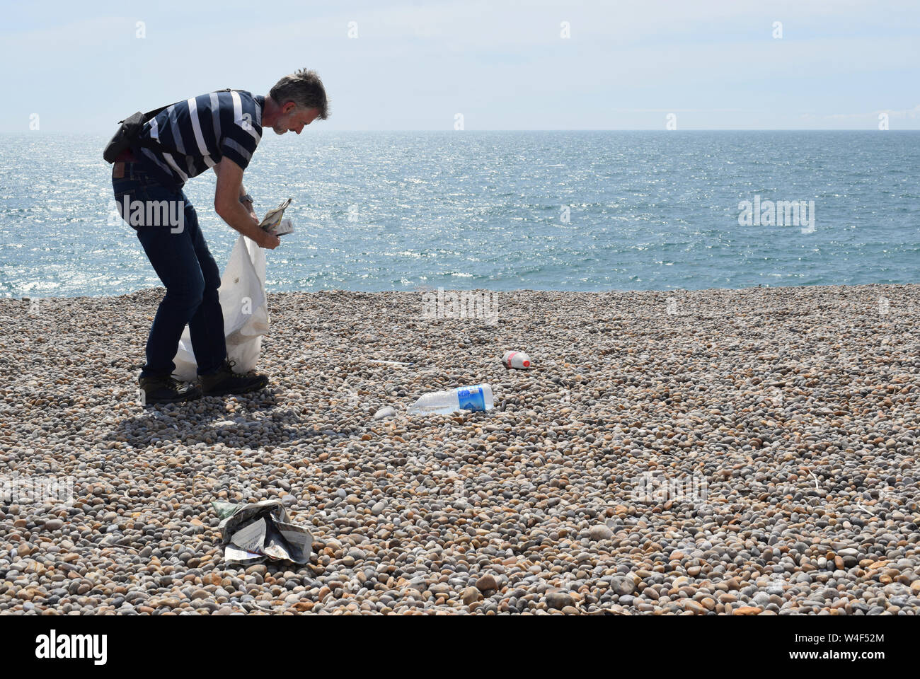 Mann, umweltbewusst, indem verworfen, Einstreu und Kunststoff Einsatz von Abfällen aus einer britischen Strand Stockfoto