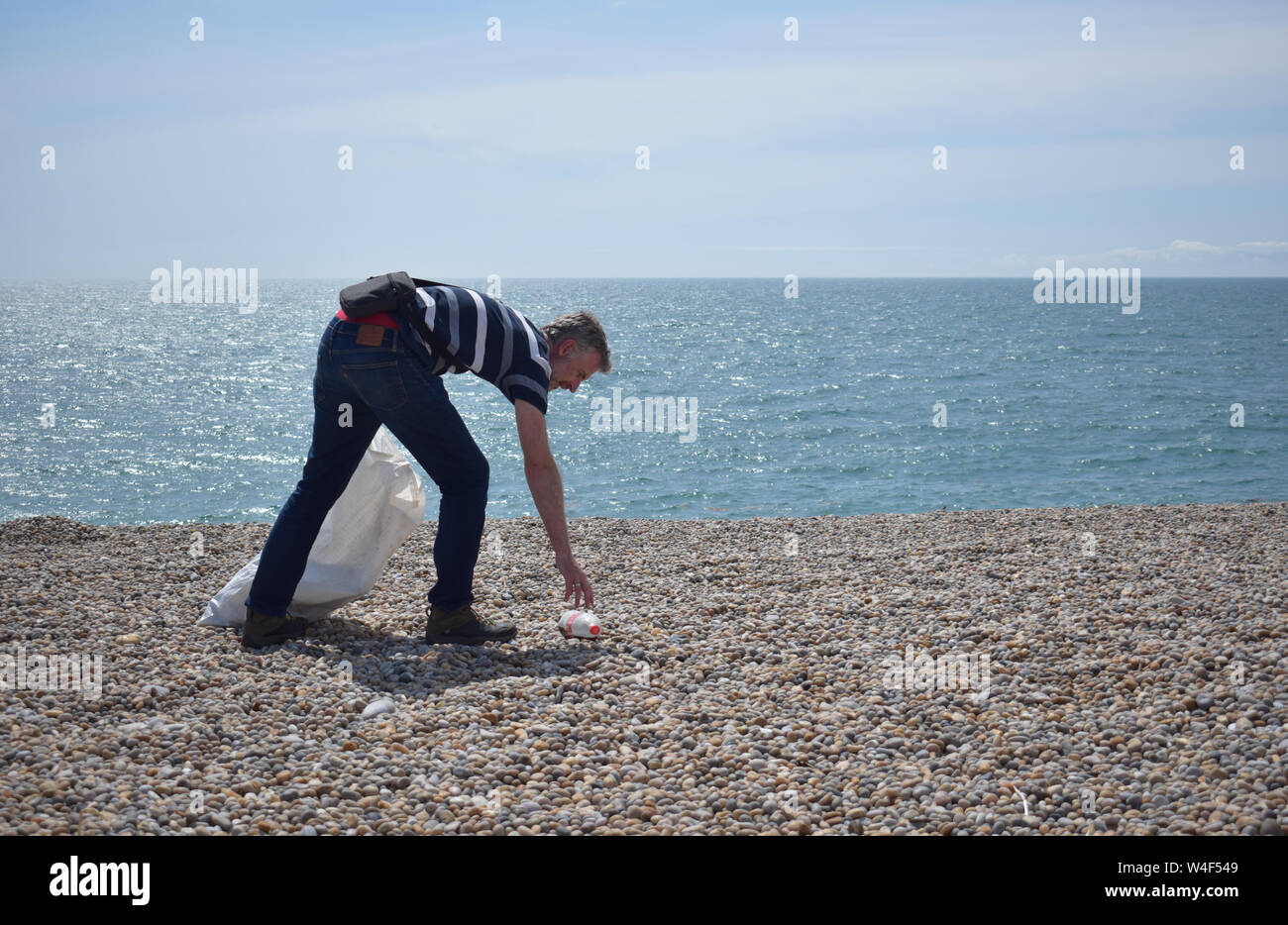 Mann, umweltbewusst, indem verworfen, Einstreu und Kunststoff Einsatz von Abfällen aus einer britischen Strand Stockfoto