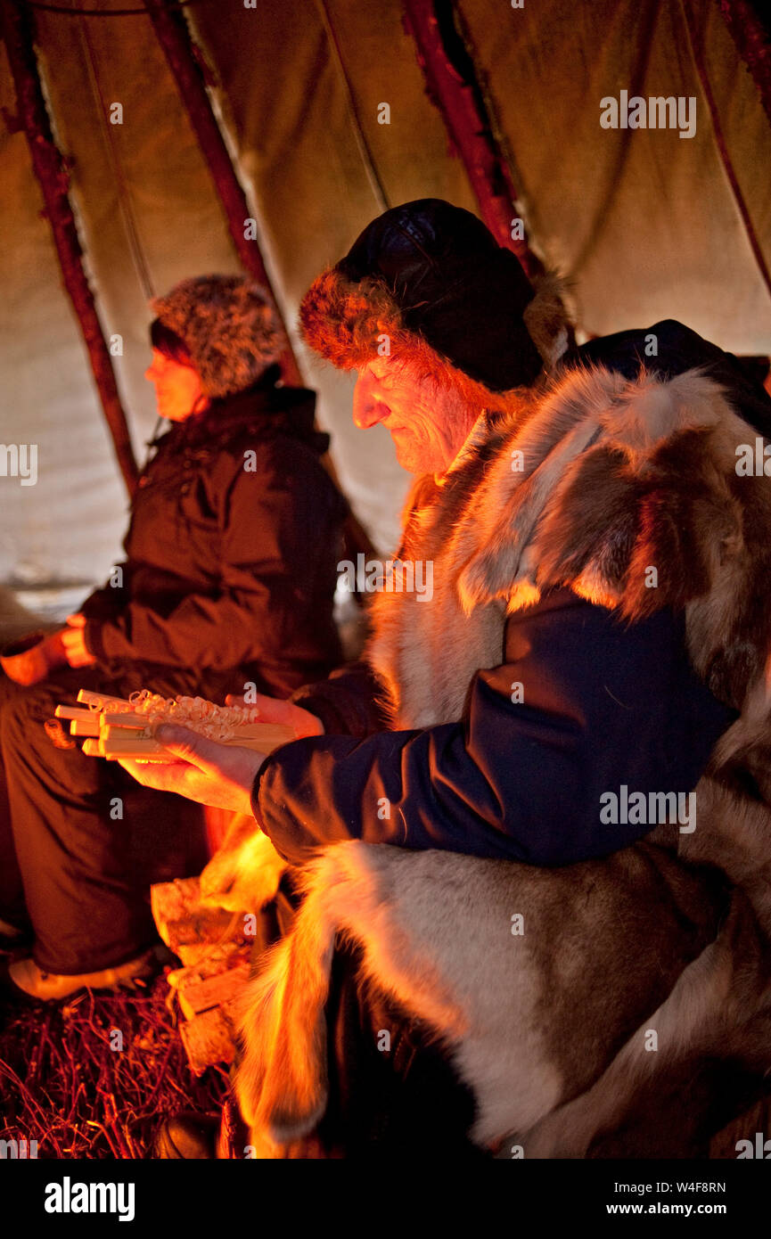 Schäfer mit seiner Visitenkarten (Stücke aus geschnitztem Holz), in der Nähe des brazier, innerhalb der Sami traditionellen Tipi, Yllas, Lappland (oben Polarkreis), Finnland Stockfoto