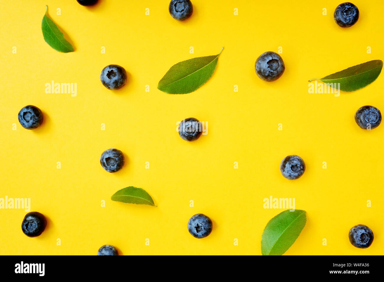 Sommer Heidelbeeren mit Blatt auf gelben Hintergrund. Beeren design Hintergrund. Nahaufnahme, Ansicht von oben oder flach Stockfoto