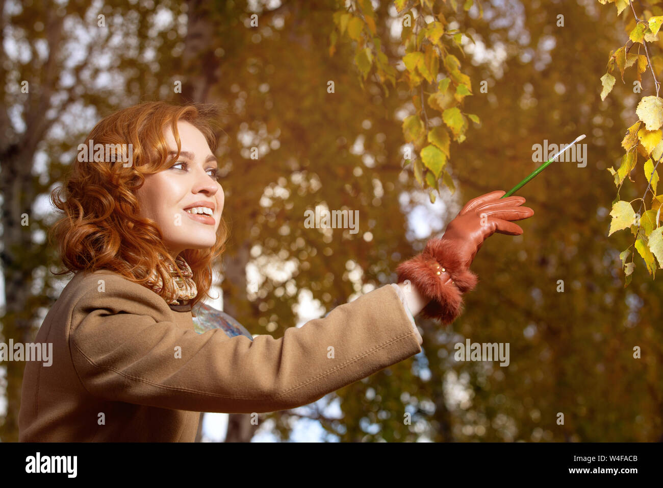 Schöne Frau mit Palette und Pinsel Lacke Farben Blätter an den Bäumen Stockfoto