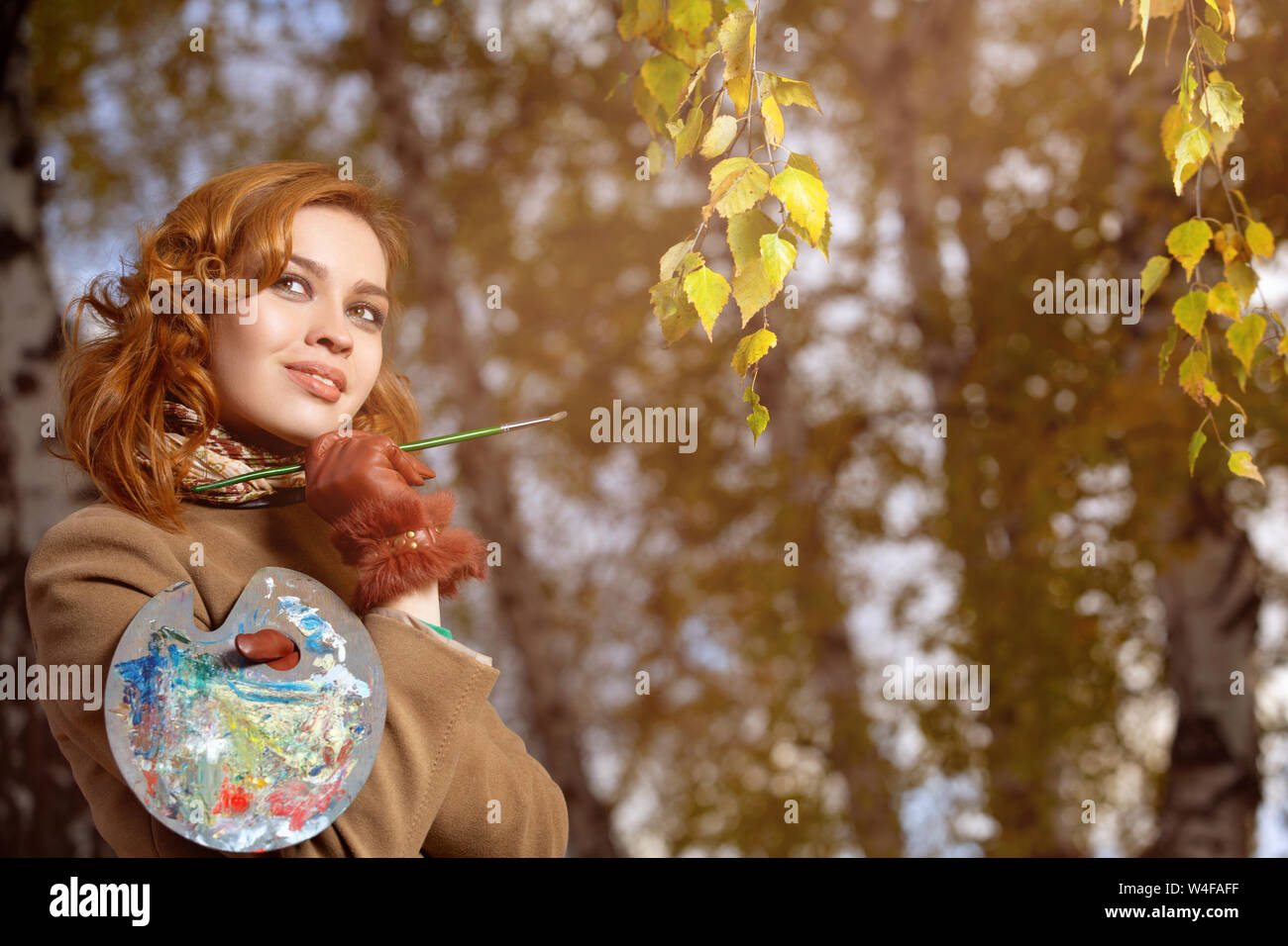 Junge Frau mit Palette und Pinsel im Freien im Herbst Park posieren. Stockfoto