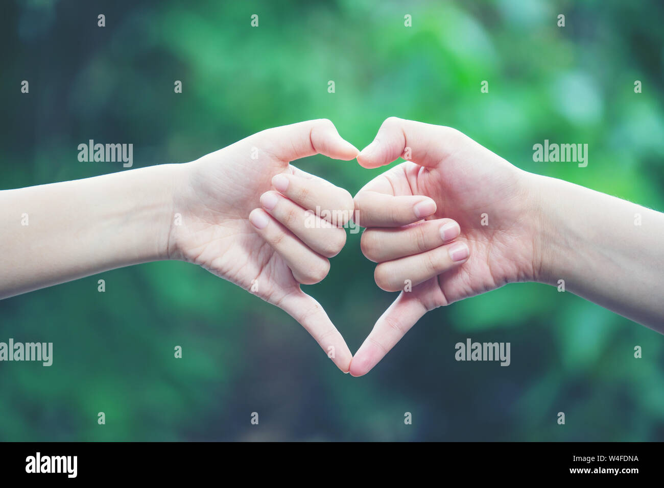 Frauen, die Herzen Formen mit der Hand auf die Natur grüner Hintergrund Stockfoto