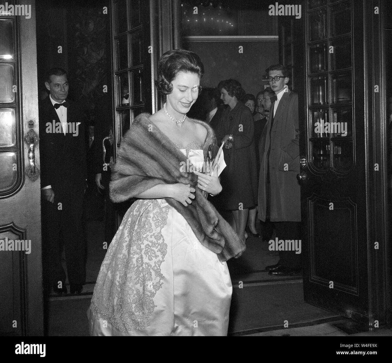 Trägt ein trägerloses Abend - Kleid, eine funkelnde Halskette und ein Fell wickeln, Prinzessin Margaret kommt an der Apollo Theater, London, Die "Stücke von acht "Revue zu sehen. Stockfoto