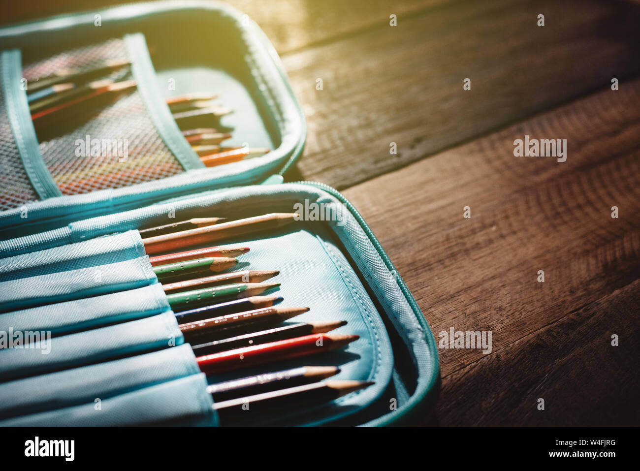 Stumpfer Farbstift in einem Federmäppchen auf einer hölzernen Schreibtisch in ein düsteres Licht. Konzept einer Bildung, Kindheit und Kreativität Stockfoto